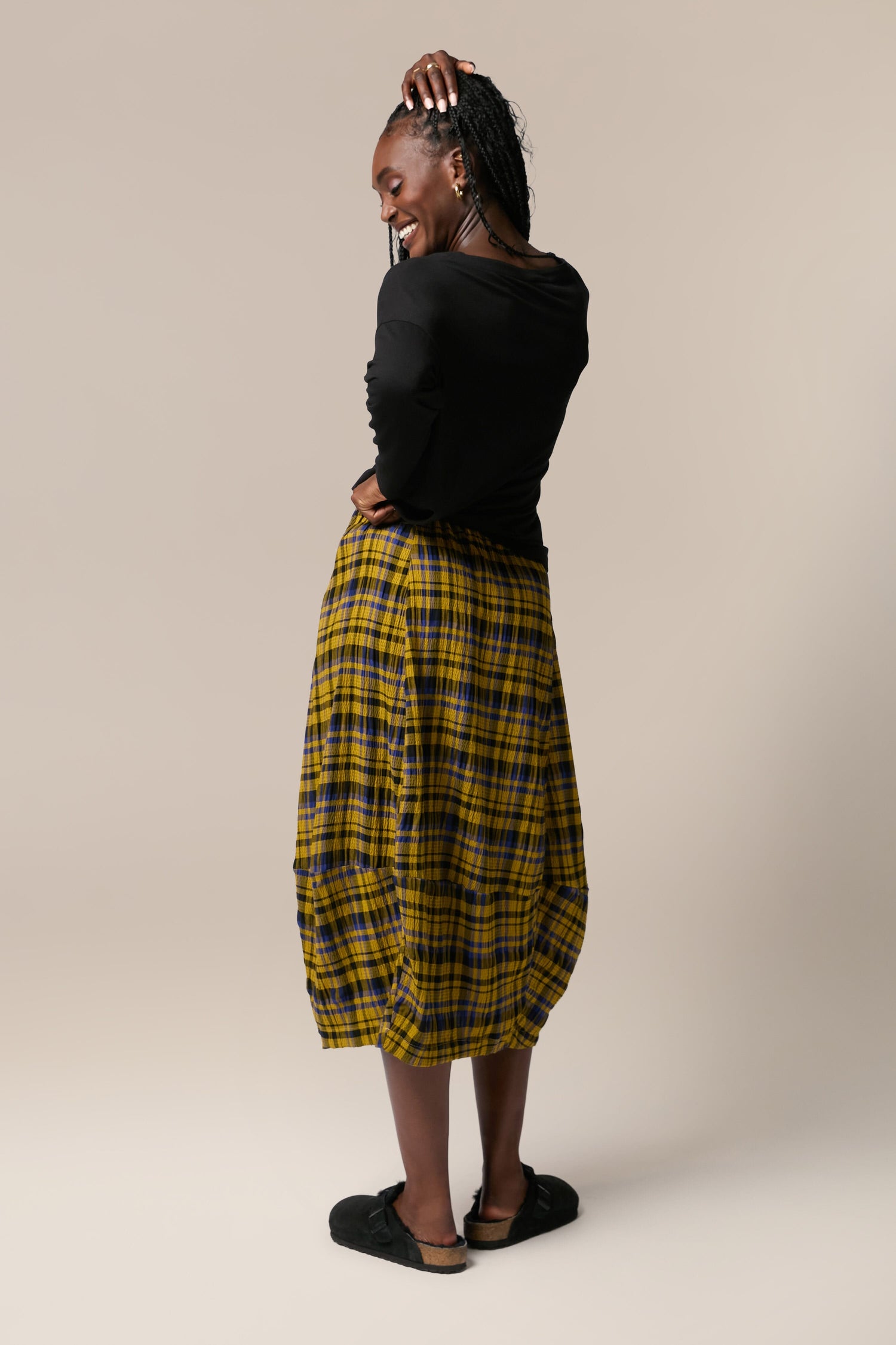 A woman wearing a Crinkle Check Skirt with an elasticated waist.