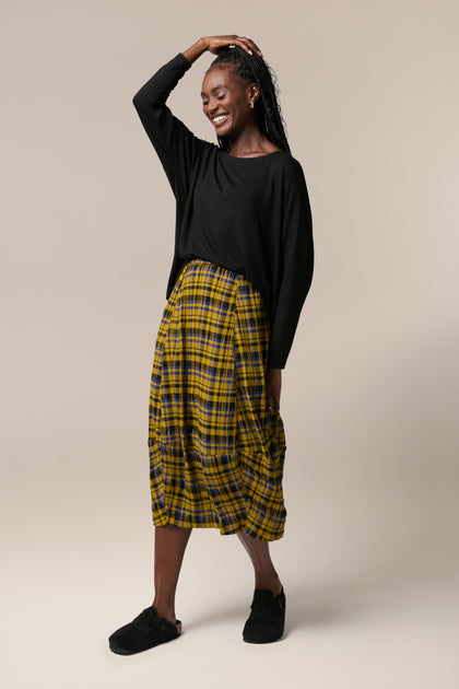 A woman wearing a yellow Crinkle Check Skirt with a check pattern.
