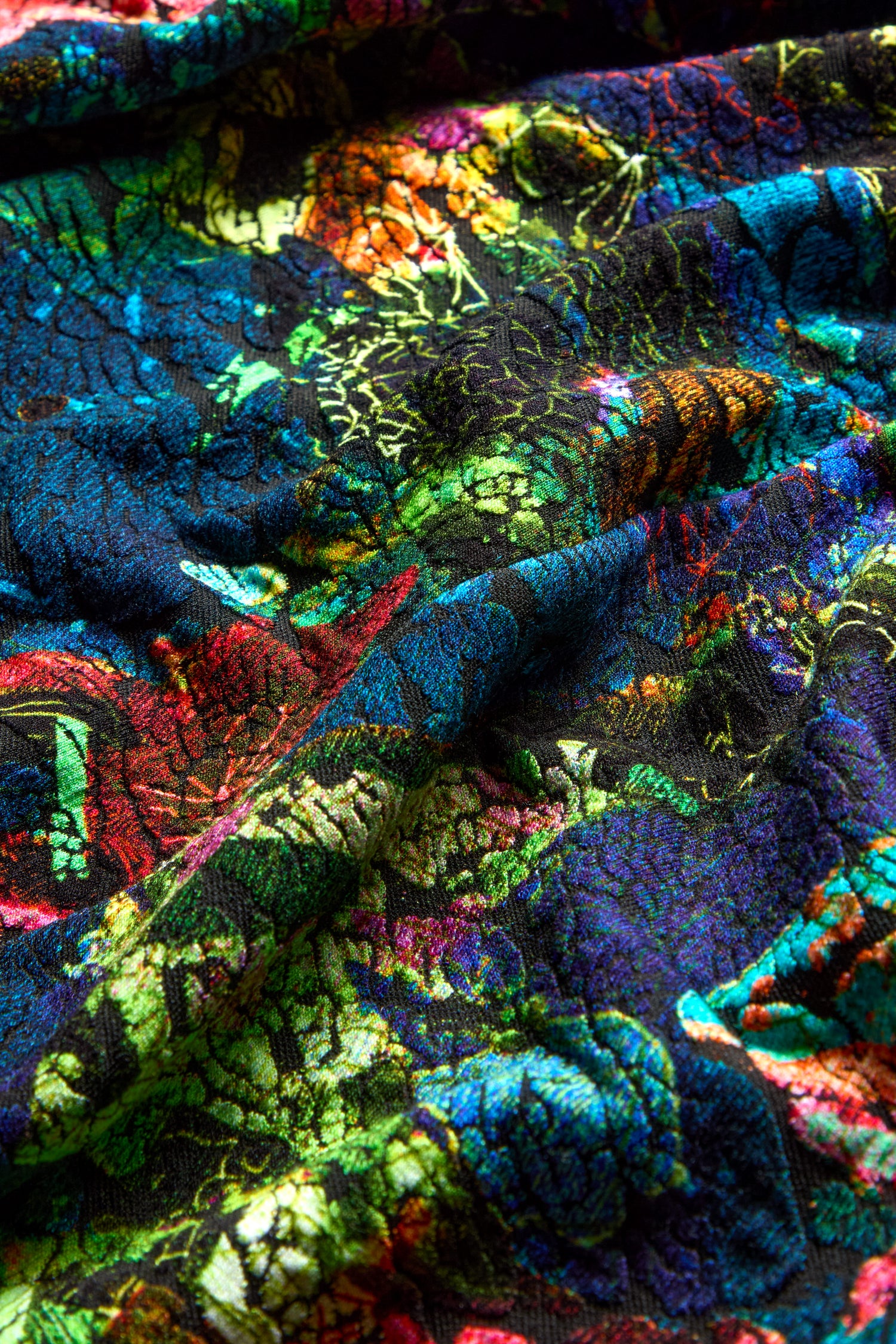 Close-up of the vibrant, textured fabric used in the Abstract Floral Jersey Cowl Neck Top, showcasing an abstract floral pattern with shades of blue, green, red, and orange.