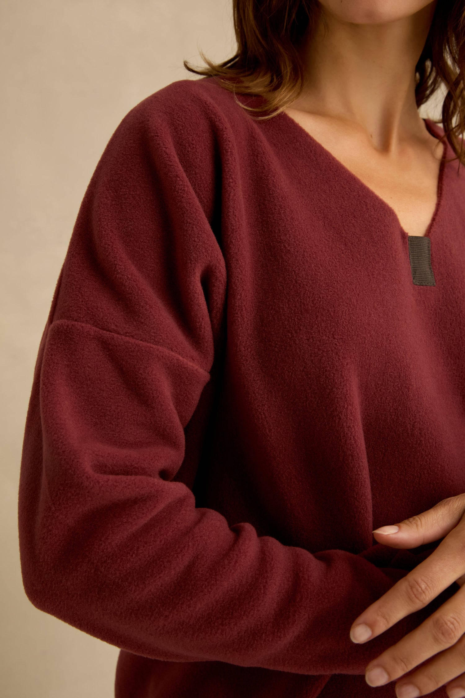 Person wearing a Dusty Pink V Neck Fleece Tunic by Henriette Steffensen, shown from shoulders to waist, with one hand resting on their side. The long-sleeved top features a soft fleece texture and flattering V-neckline—also available in burgundy.