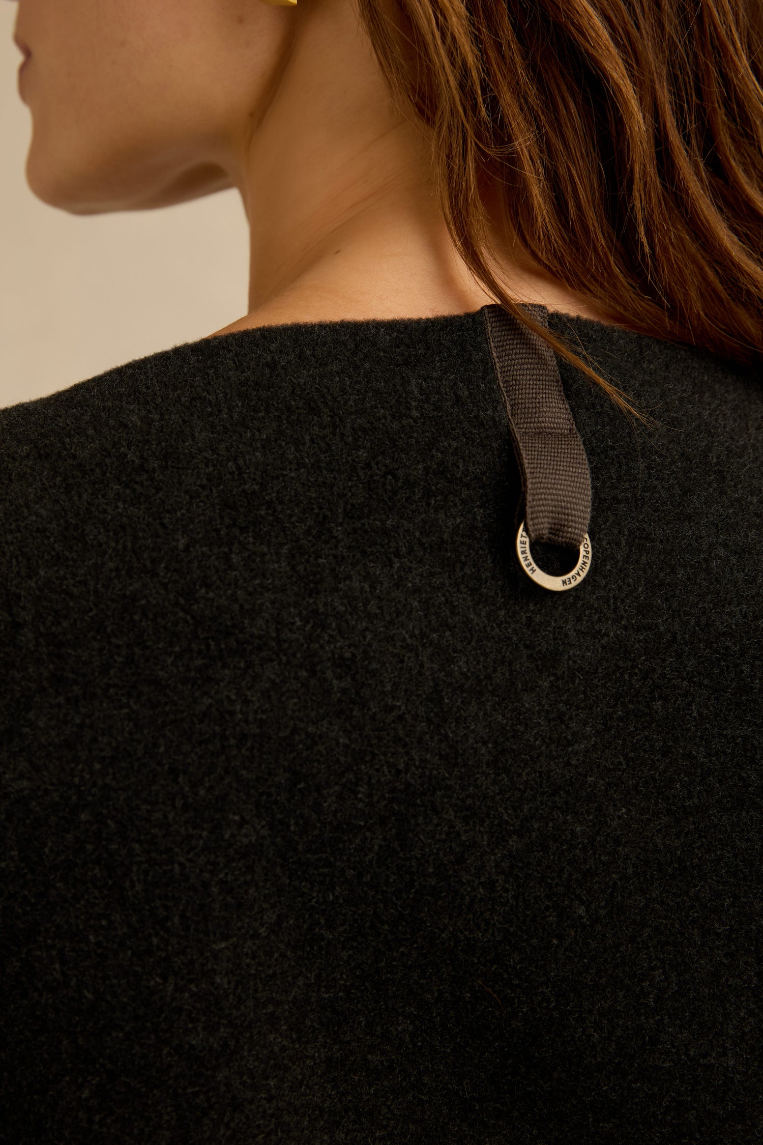 Close-up of a person wearing the Colour Block Fleece Boxy Top by Henriette Steffensen, featuring black textured fabric with a brown fabric loop and a small metallic ring attached to the back neckline in a contemporary boxy fit.