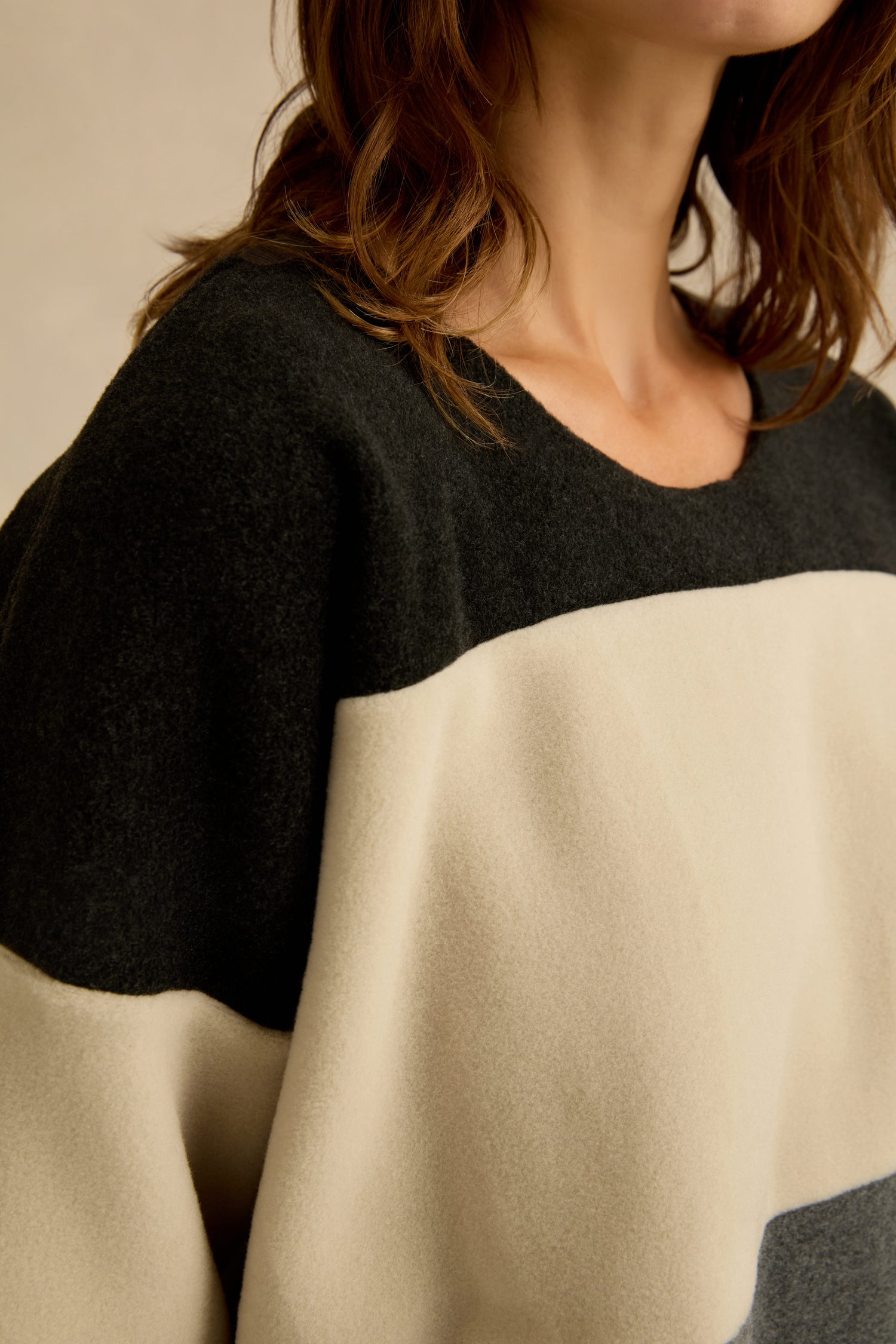 A person with shoulder-length brown hair wears the Colour Block Fleece Boxy Top in black and cream tones, echoing an effortlessly stylish look.