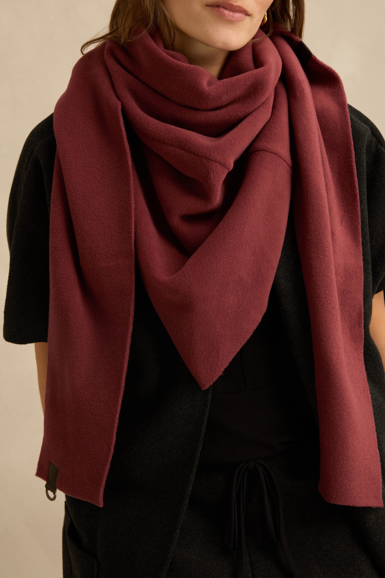 Woman wearing a dark outfit with a large, deep red Triangle Scarf by Henriette Steffensen draped around her neck and shoulders, shown from shoulders to mid-torso.