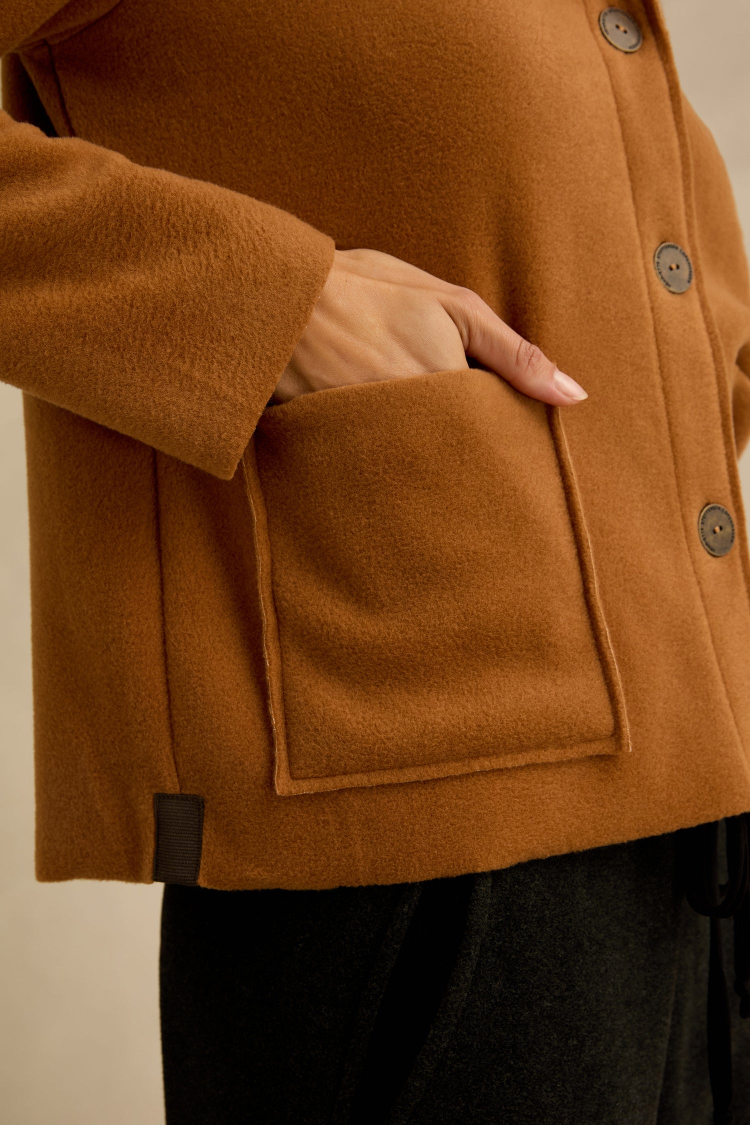 A person wearing the Rust Fleece Fitted Jacket with one hand in the front pocket, shown from shoulder to upper thigh.