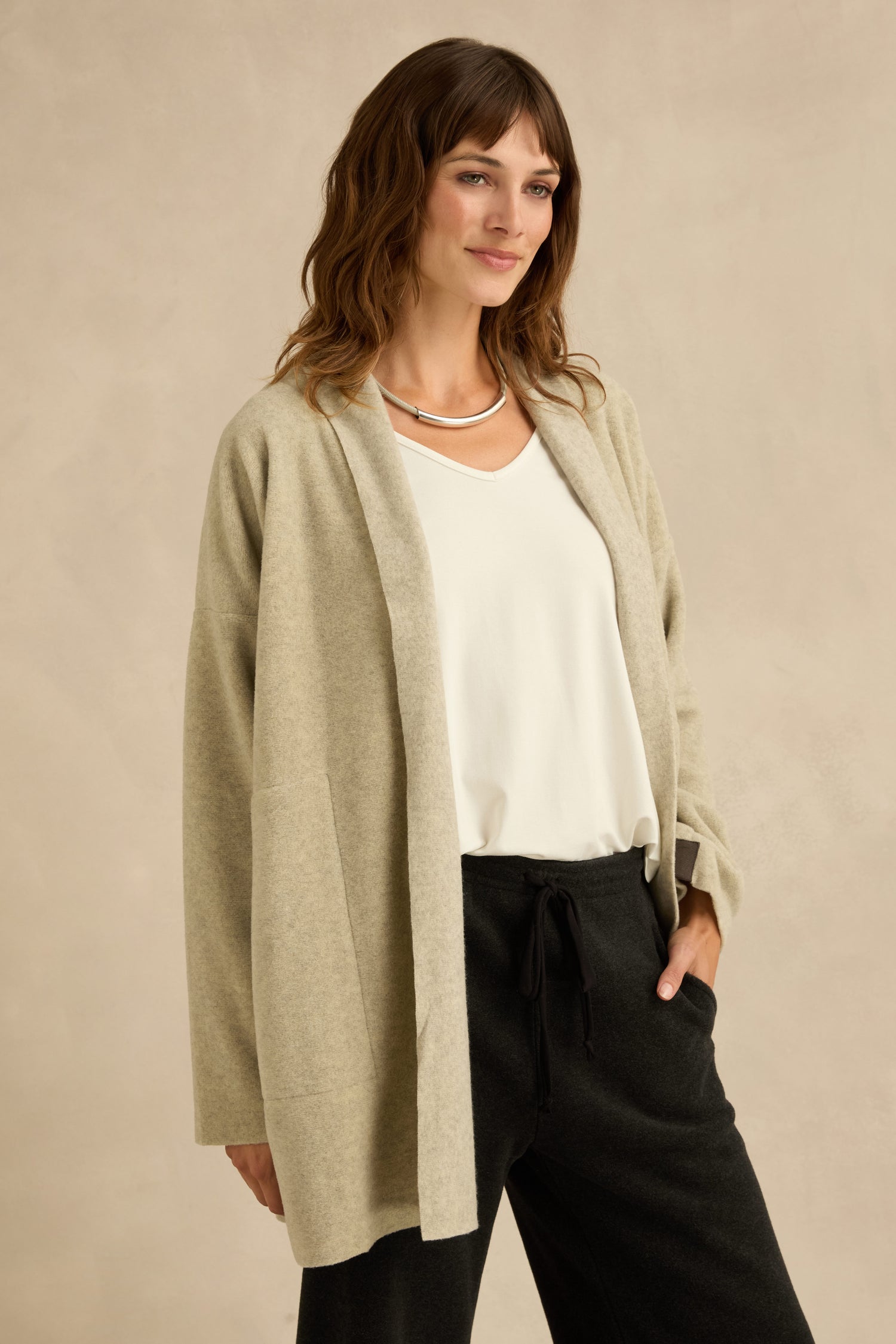 Woman wearing a Cream Marl Fleece Cardigan over a white top and black pants stands against a neutral background.