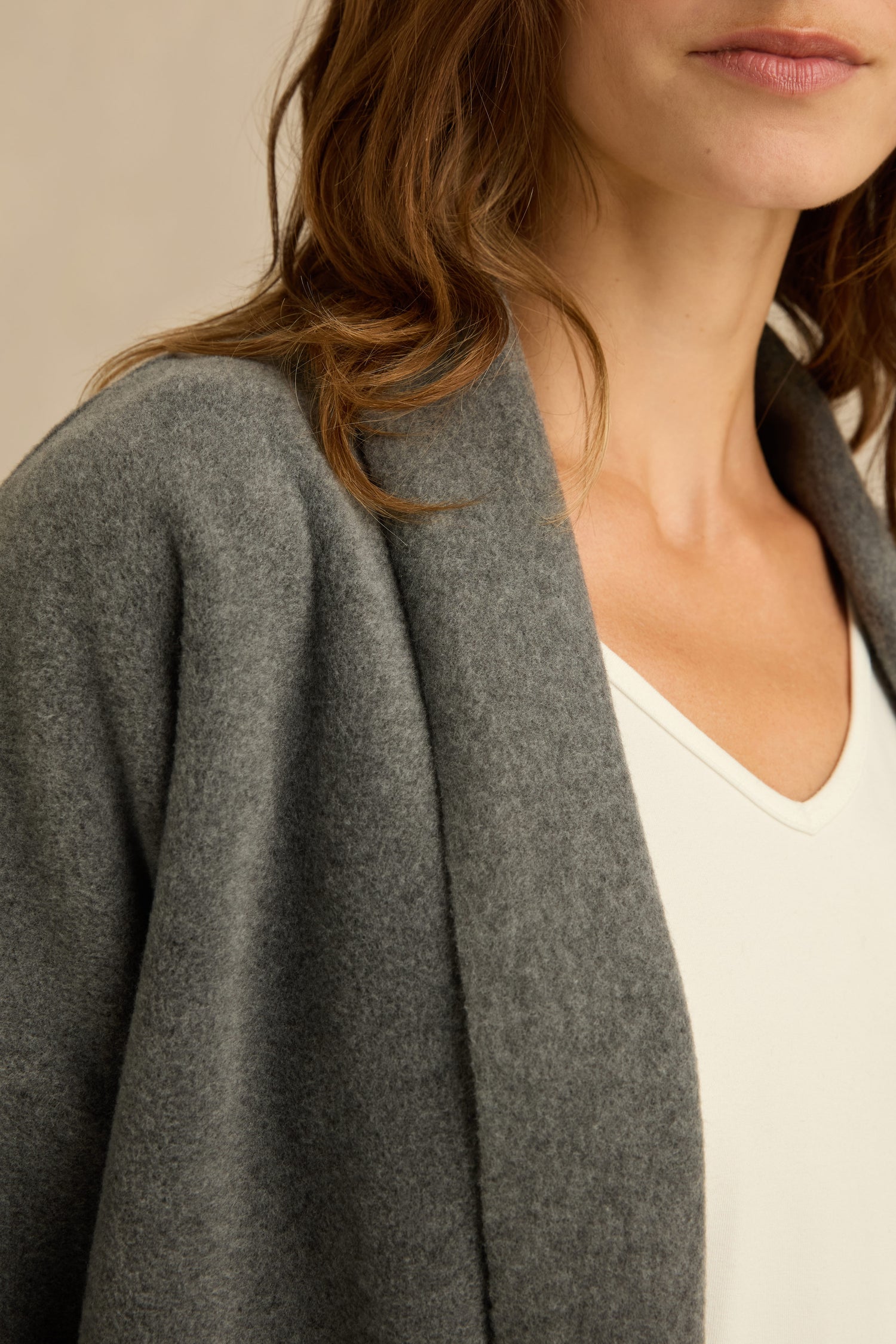 A woman wearing a relaxed fit Grey Fleece Cardigan over a white V-neck top, visible from shoulder to lips, against a neutral background.