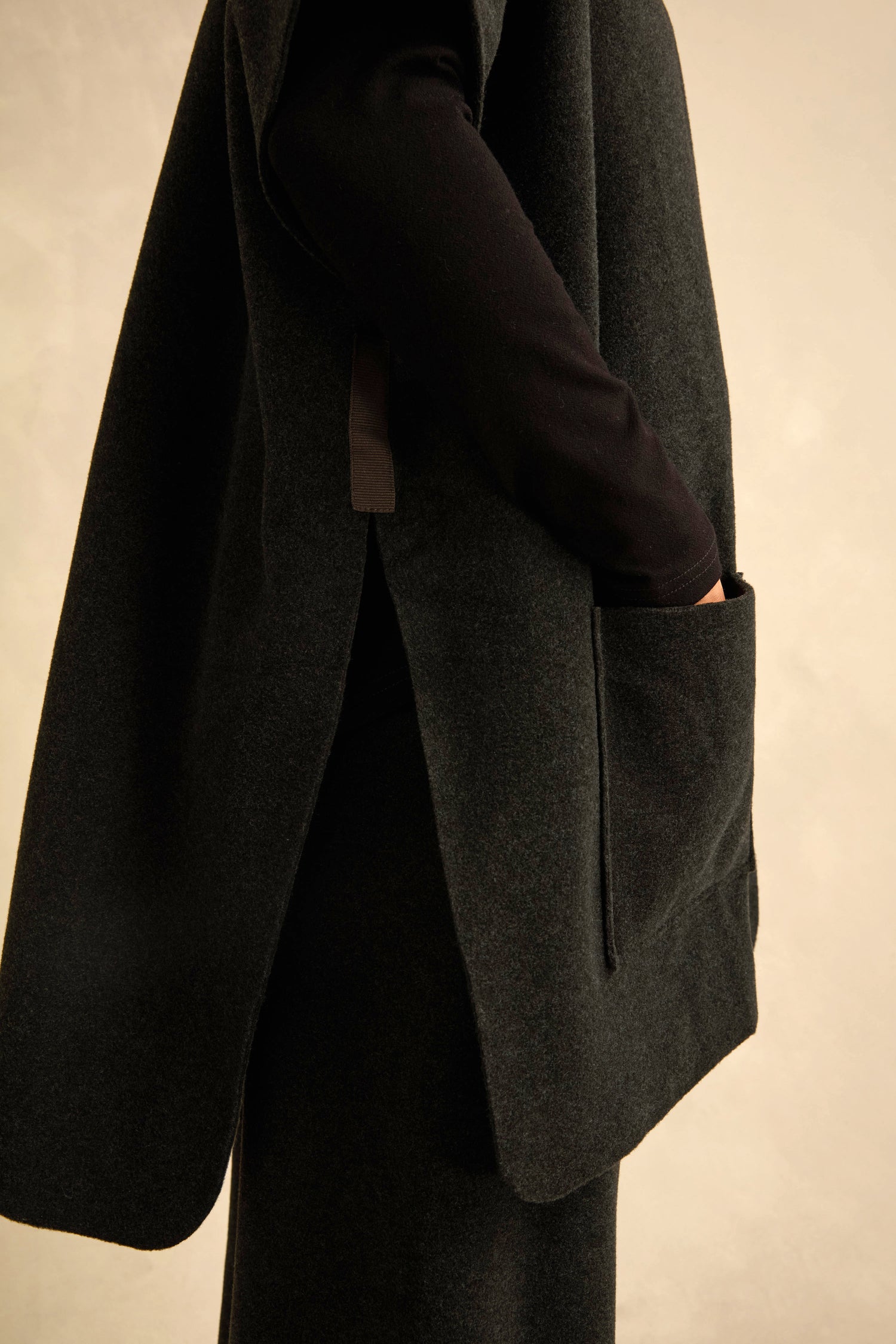 A person wearing a dark Short Sleeve Fleece Gilet with a side pocket, a black long-sleeve top featuring kimono-style sleeves, and a dark skirt, shown from the side against a neutral background.