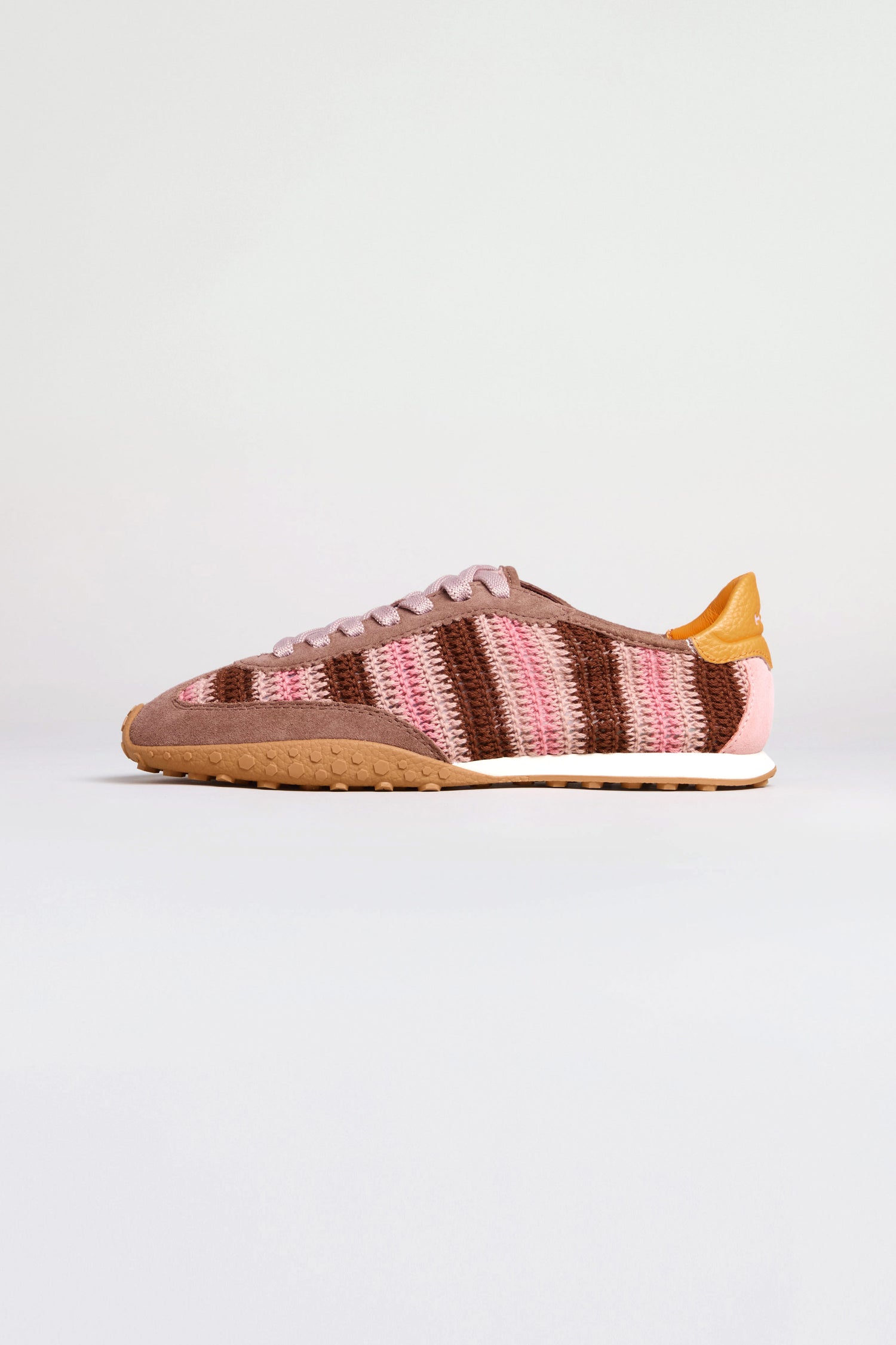 The Bridge Woven Brown Crochet Trainers feature pink, brown, and tan woven stripes, a cushioned sole, gum outsole, and tan leather heel accent—shown on a plain white background.