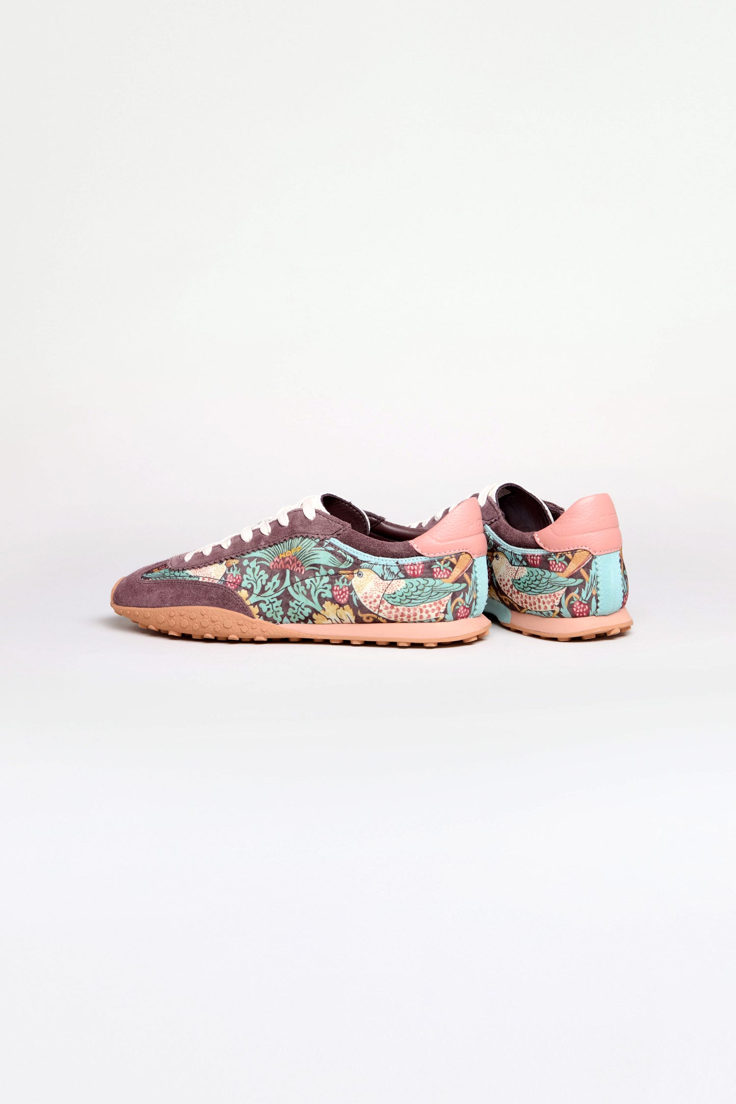 A pair of William Morris Bridge Trainers with a Strawberry Thief print, featuring floral and bird patterns, pink accents, and light brown soles, displayed against a plain white background.
