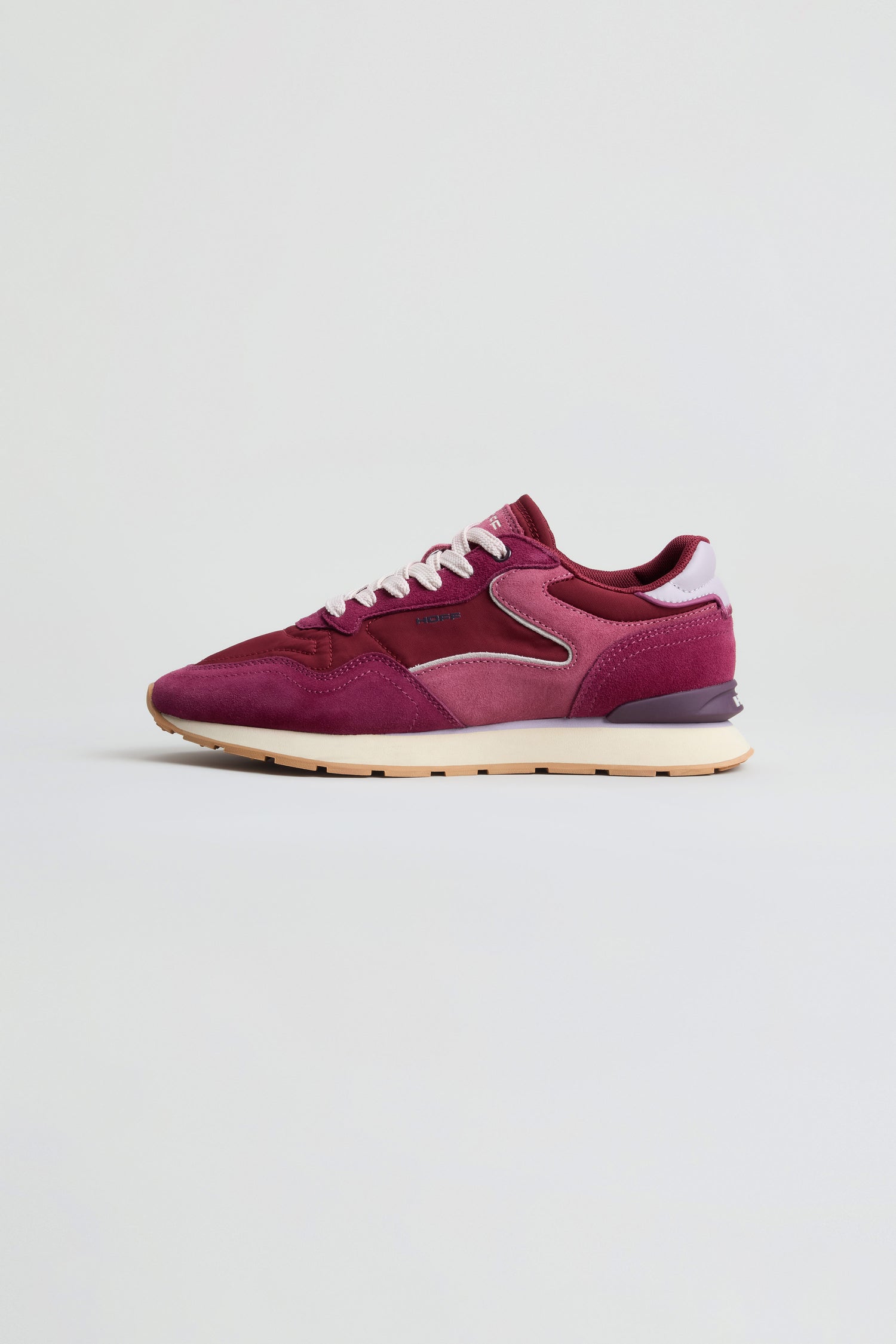 A single City Trainers sneaker in maroon and pink, featuring white laces and a retro running design, is displayed in side profile against a plain light background.