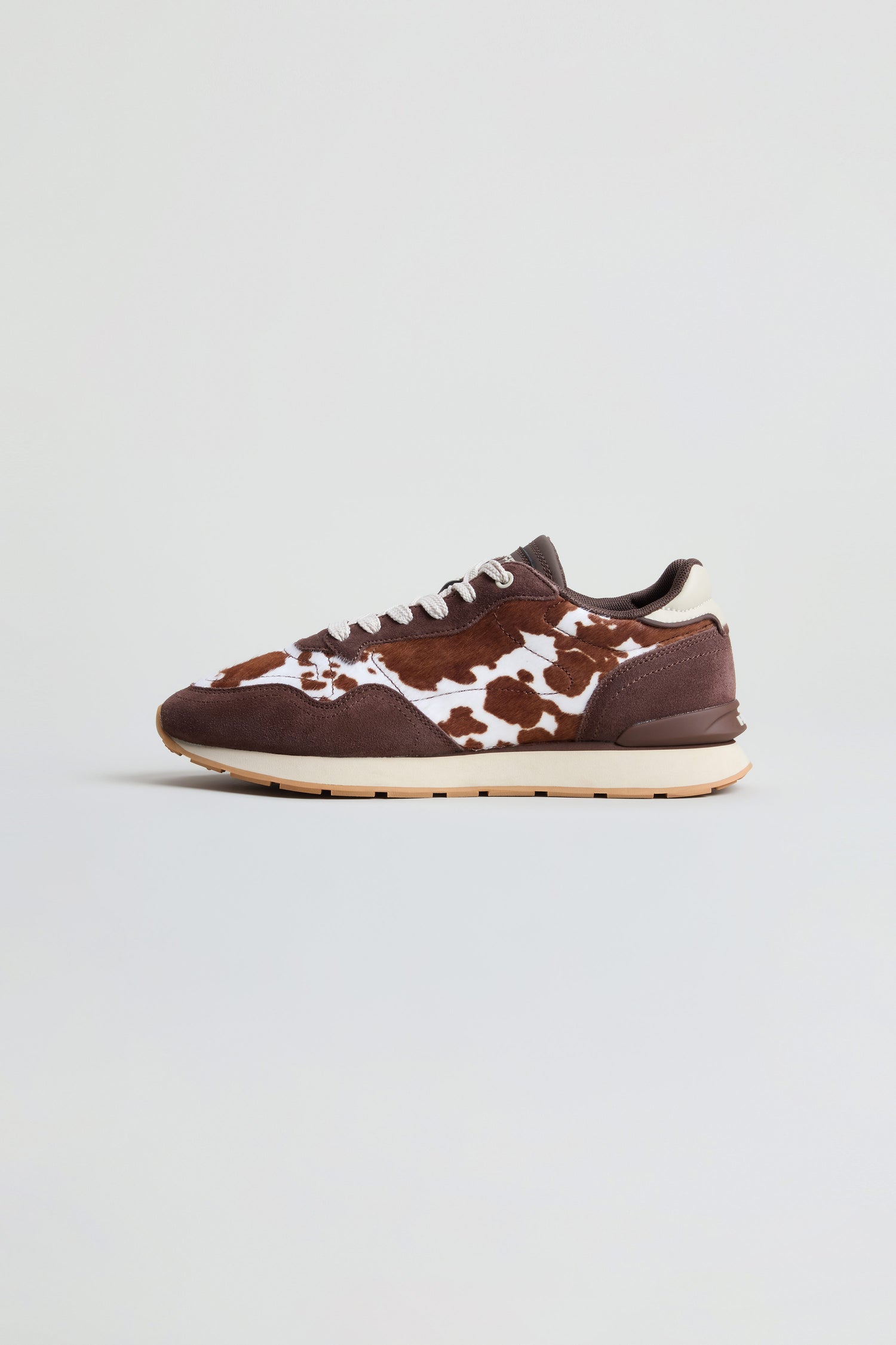 Animal Print City Trainers in a brown and white cowhide print, crafted from premium suede with white laces and a beige sole, showcased against a plain light background.