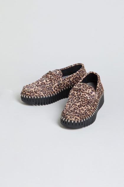Tulip Leopard Penny Loafers featuring a bold brown leopard print and thick black grooved wedge sole, slip-on style, displayed on a light gray background.