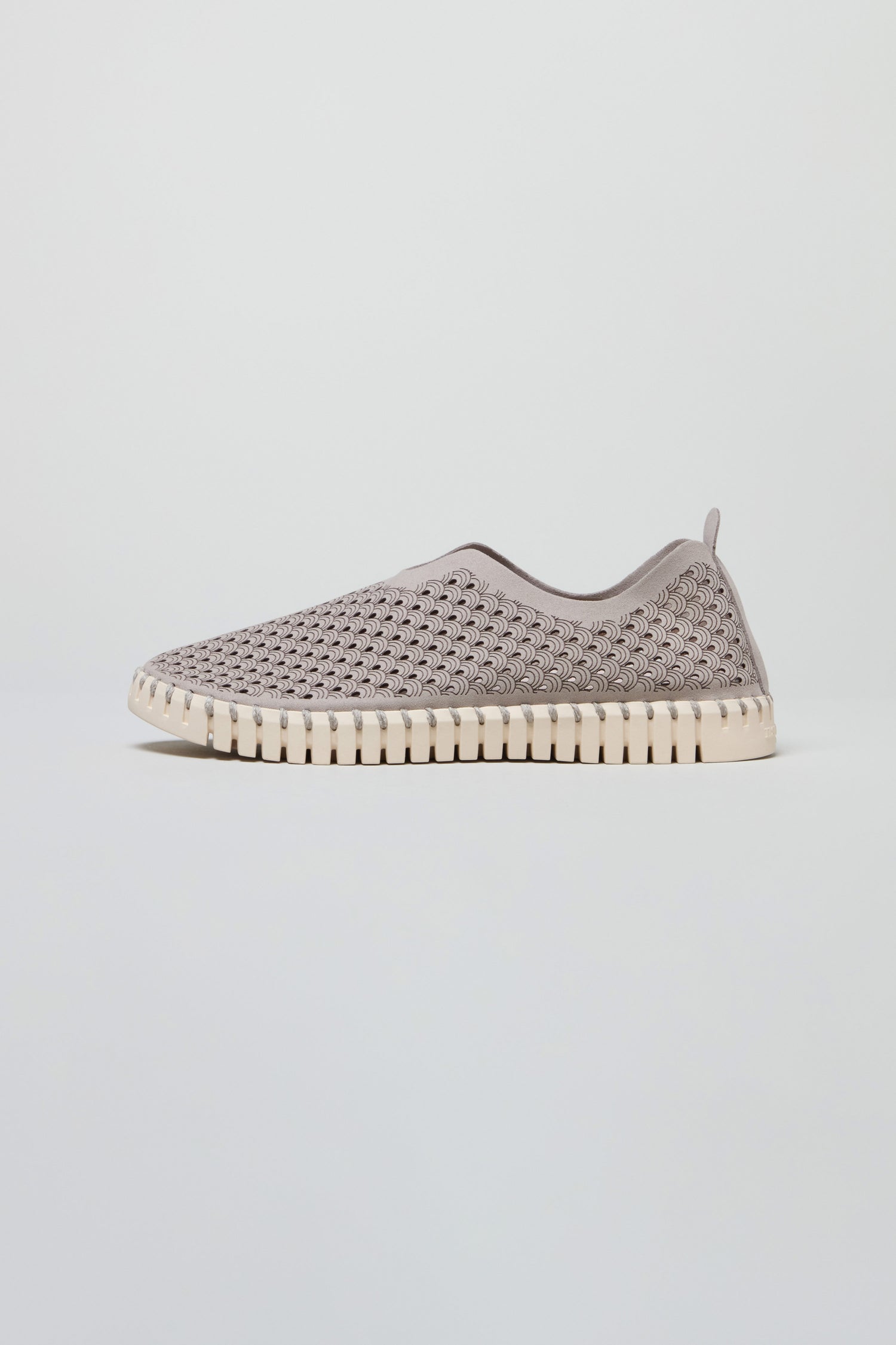 The Grey Tulip Slip On Shoes feature a light grey, perforated textured upper and a white ridged sole, highlighting Scandinavian style against a simple background.