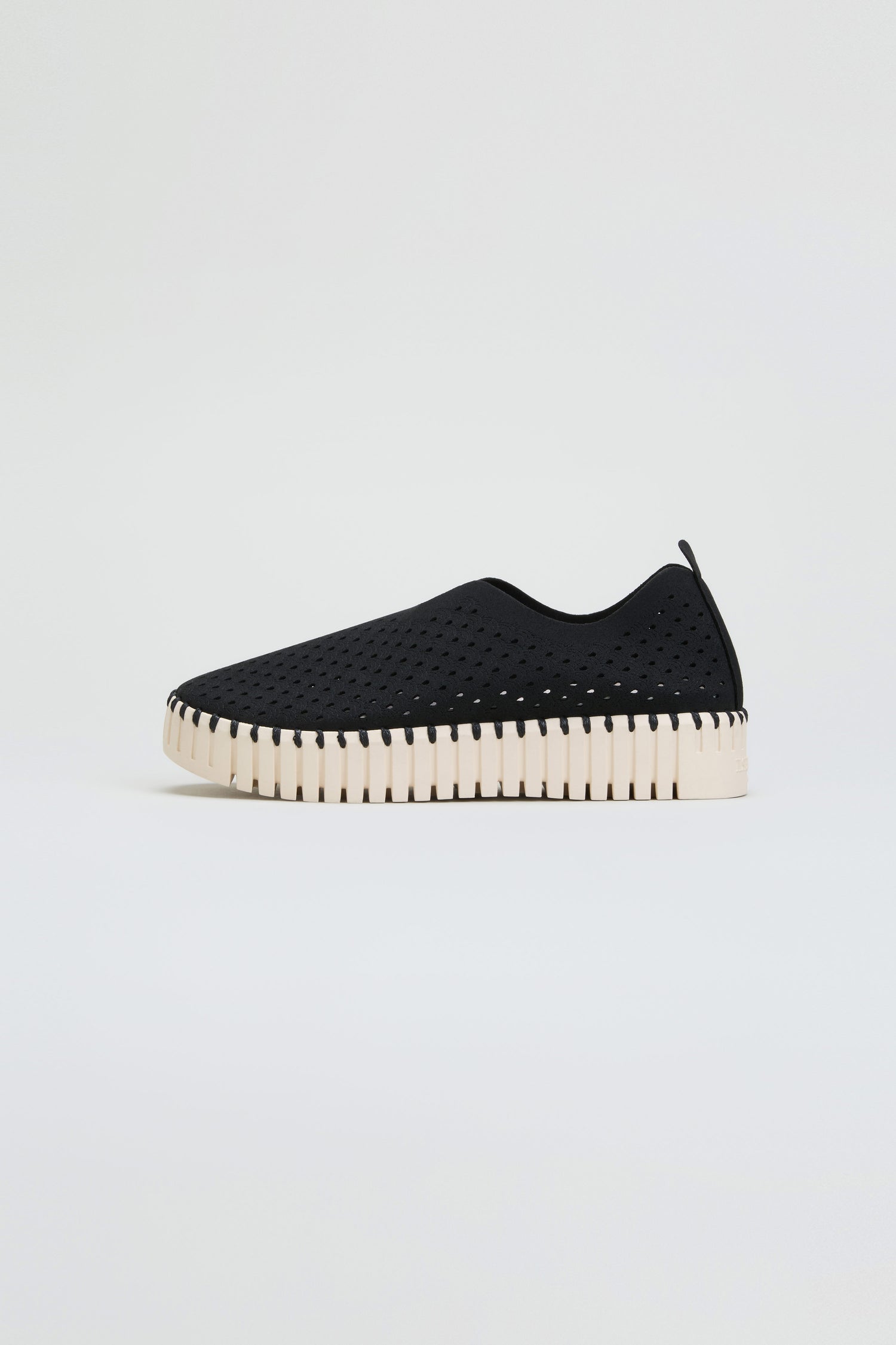 The Tulip Platform Slip On Shoes feature a breathable, perforated upper crafted from recycled microfiber and are set on a thick white sole. Shown in profile against a plain white background, these slip-on shoes combine style with sustainability.
