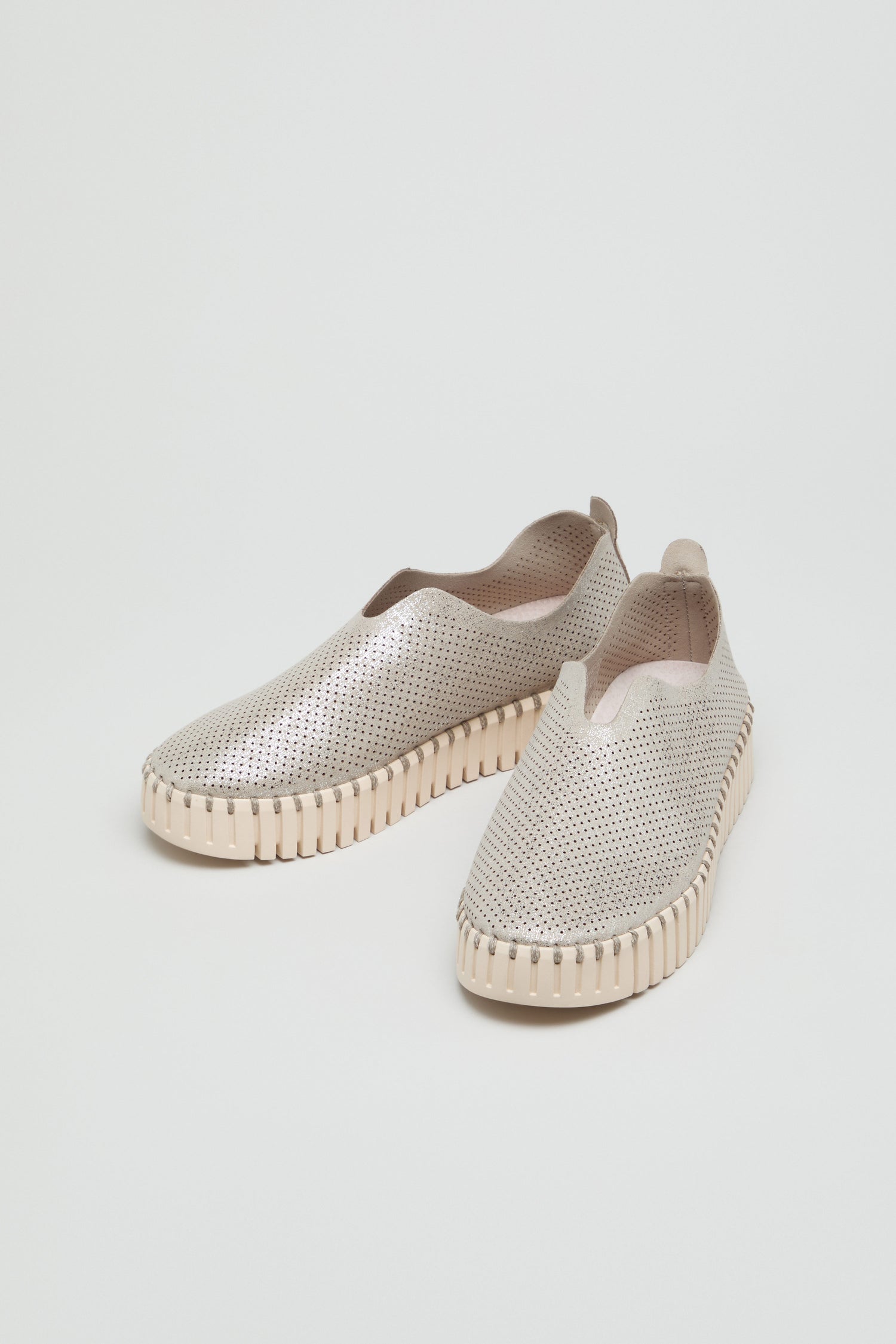 A pair of Tulip Glimmer Platform Slip On Shoes in light beige, featuring perforated uppers and ribbed, textured soles, displayed on a plain white background.