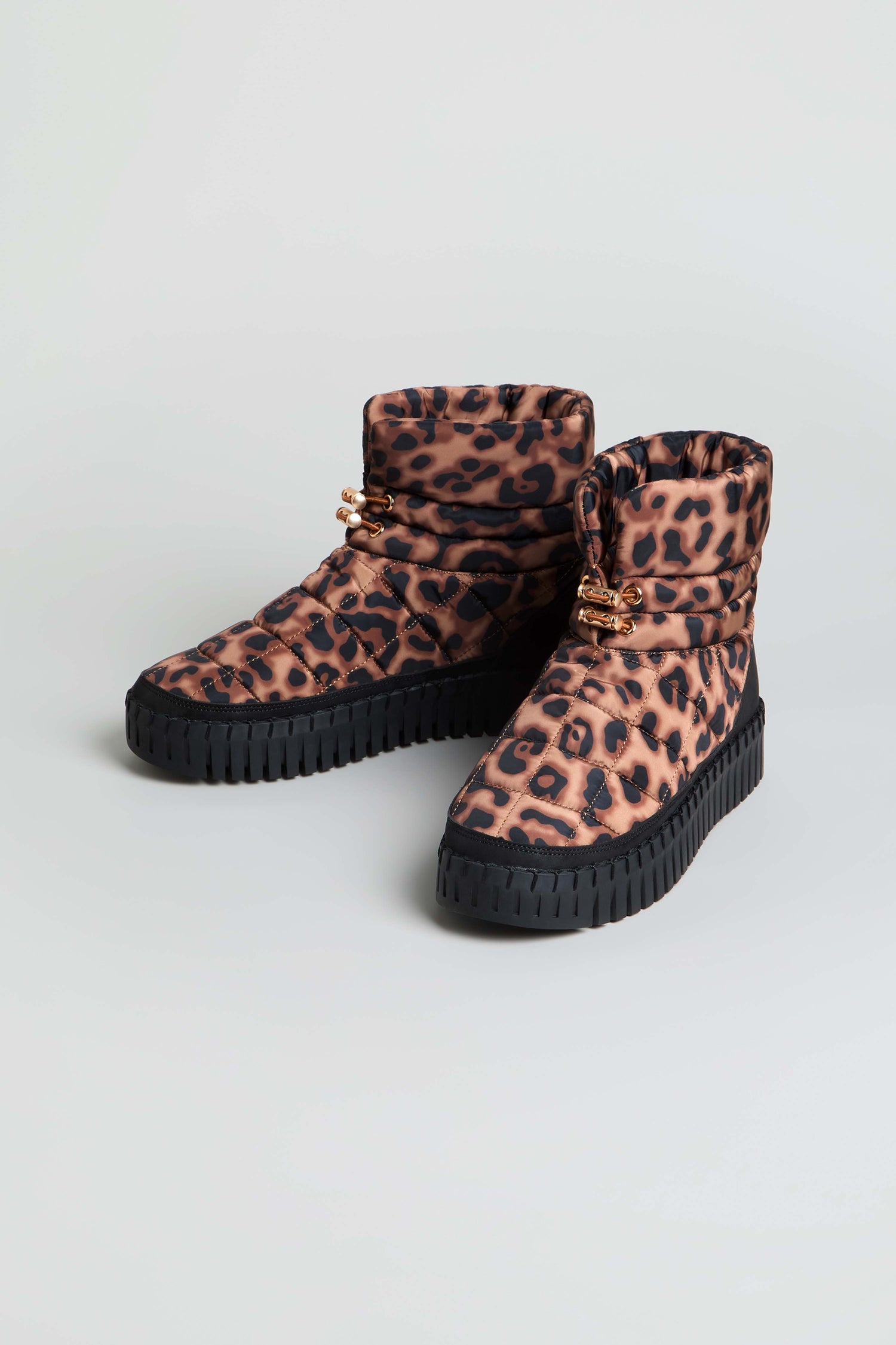 A pair of Tulip Quilted Panther Winter Boots featuring an ankle-high silhouette, a tan and black leopard print pattern, and a thick, cushioned platform sole, displayed on a neutral background.