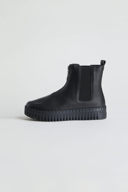 The Tulip Zip Chelsea Boots, crafted from black recycled microfibre with an elastic side panel, side zipper, pull tab, and chunky treaded sole, are displayed on a plain light background.