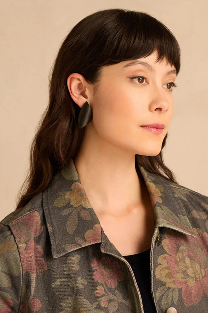 A person wearing Sculptural Mango Black Wood Earrings, featuring smooth, curved black wood.