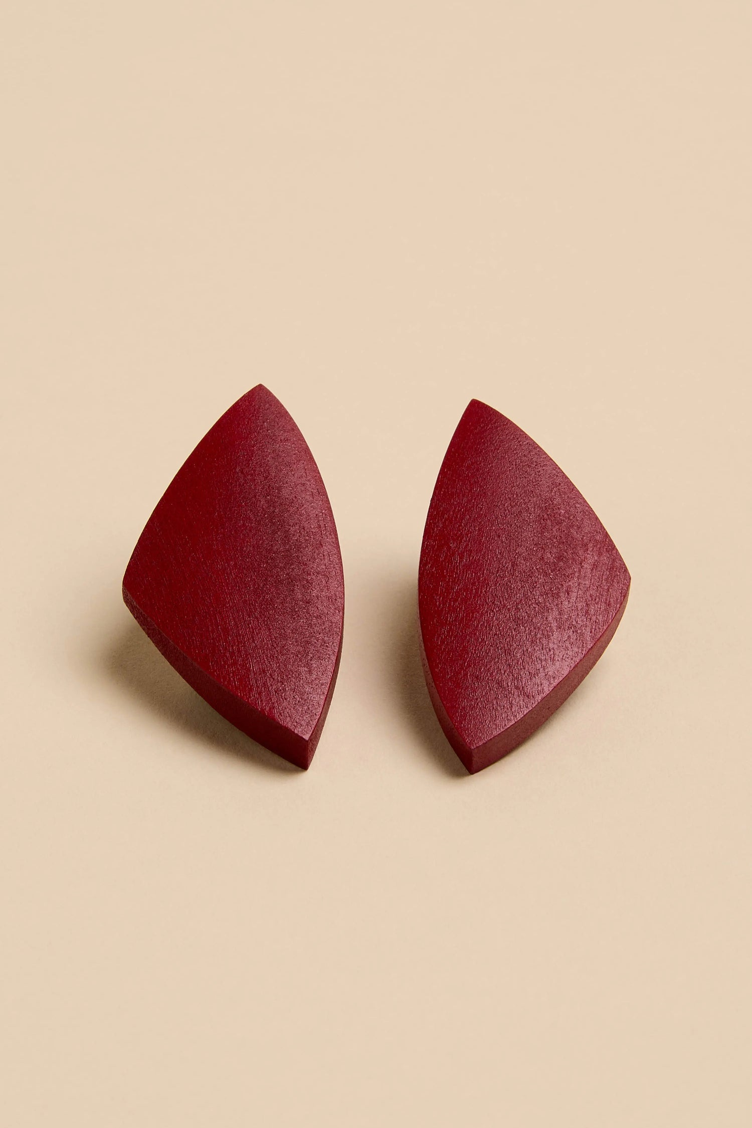 Sculptural Mango Red Wood Earrings: a pair of red, wedge-shaped sculptural mango wood earrings.