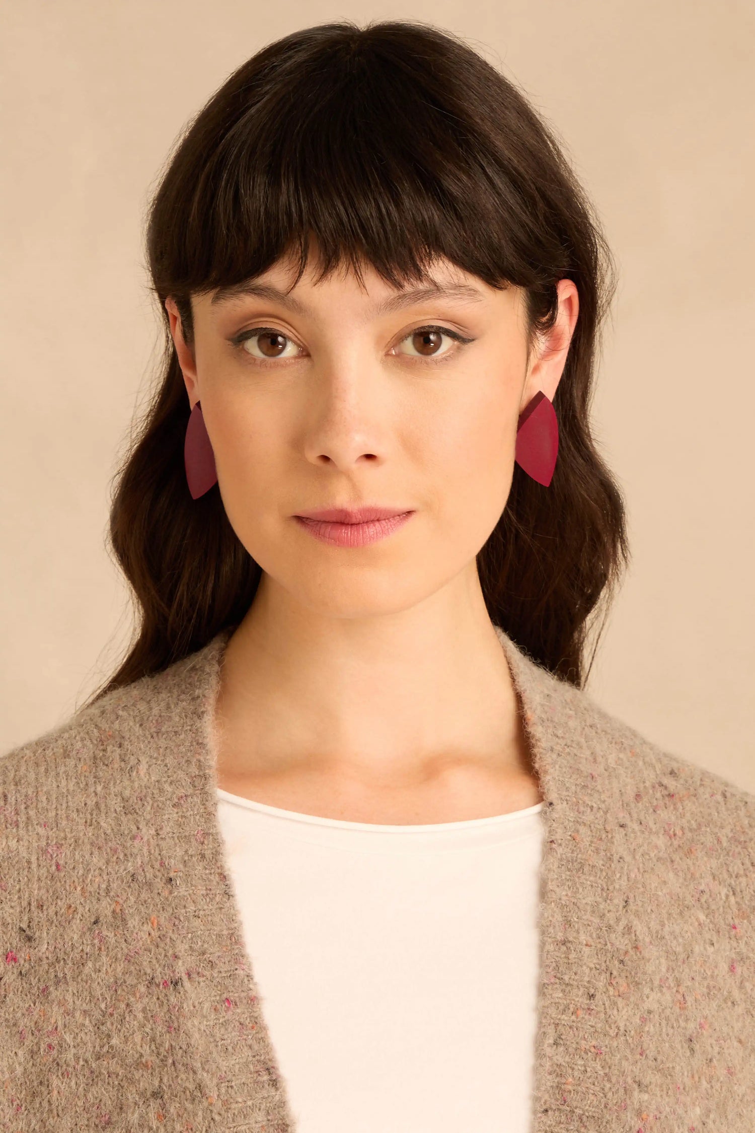A person wearing maroon, leaf-shaped Sculptural Mango Red Wood Earrings.
