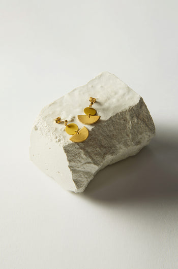 Colour Pop Semi Circle Earrings, crafted with circular and semi-circular designs in gold, elegantly rest on a textured white stone surface. These minimalist earrings add a touch of sophistication to any outfit.