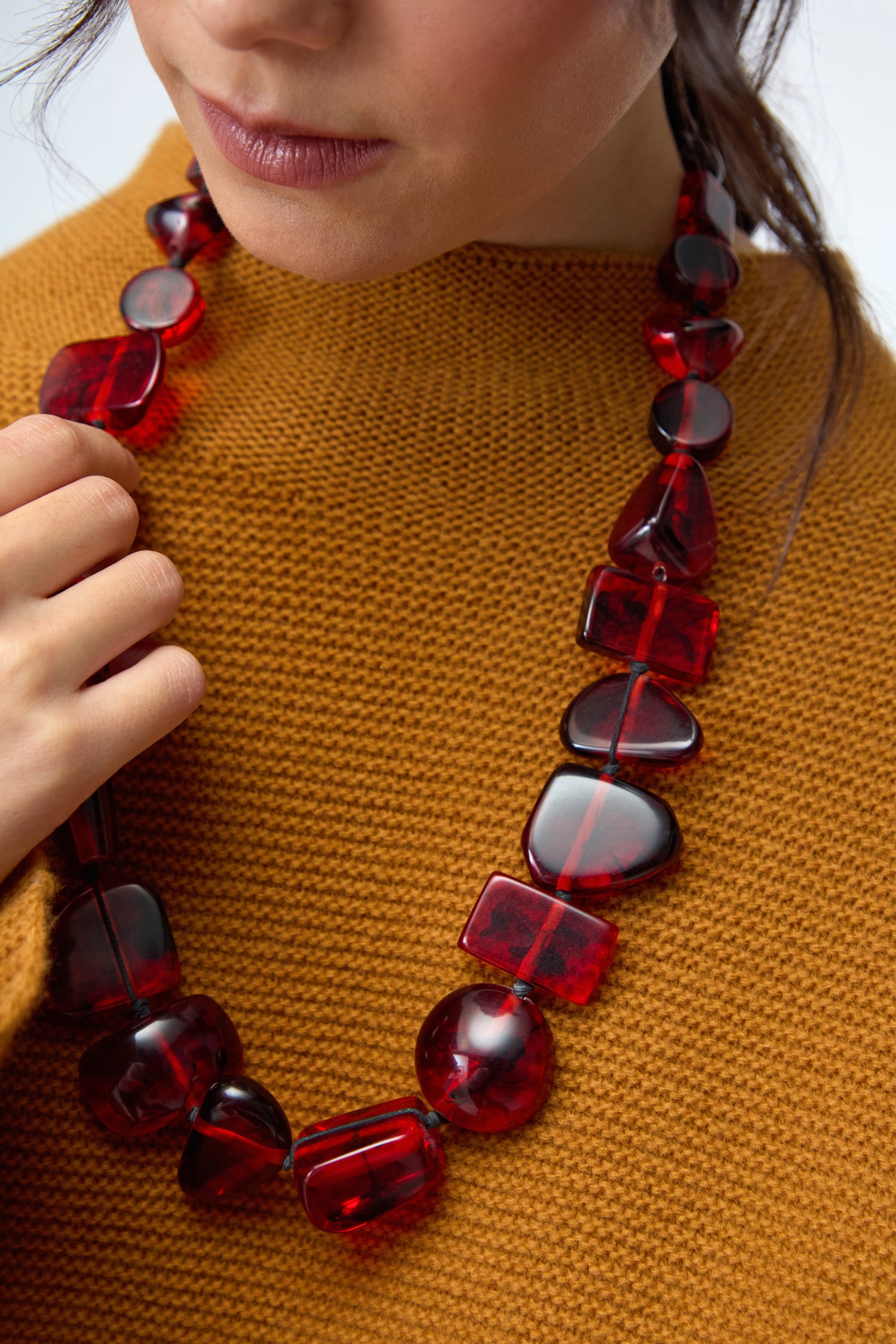 A woman, shown from the shoulders up, wears the Ruby Resin Bead Necklace and a textured mustard sweater.