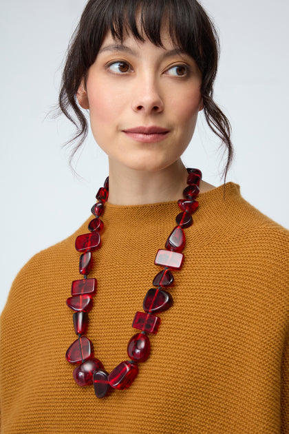 A woman wearing a mustard brown knit top and the Ruby Resin Bead Necklace gazes slightly to the right against a plain background.