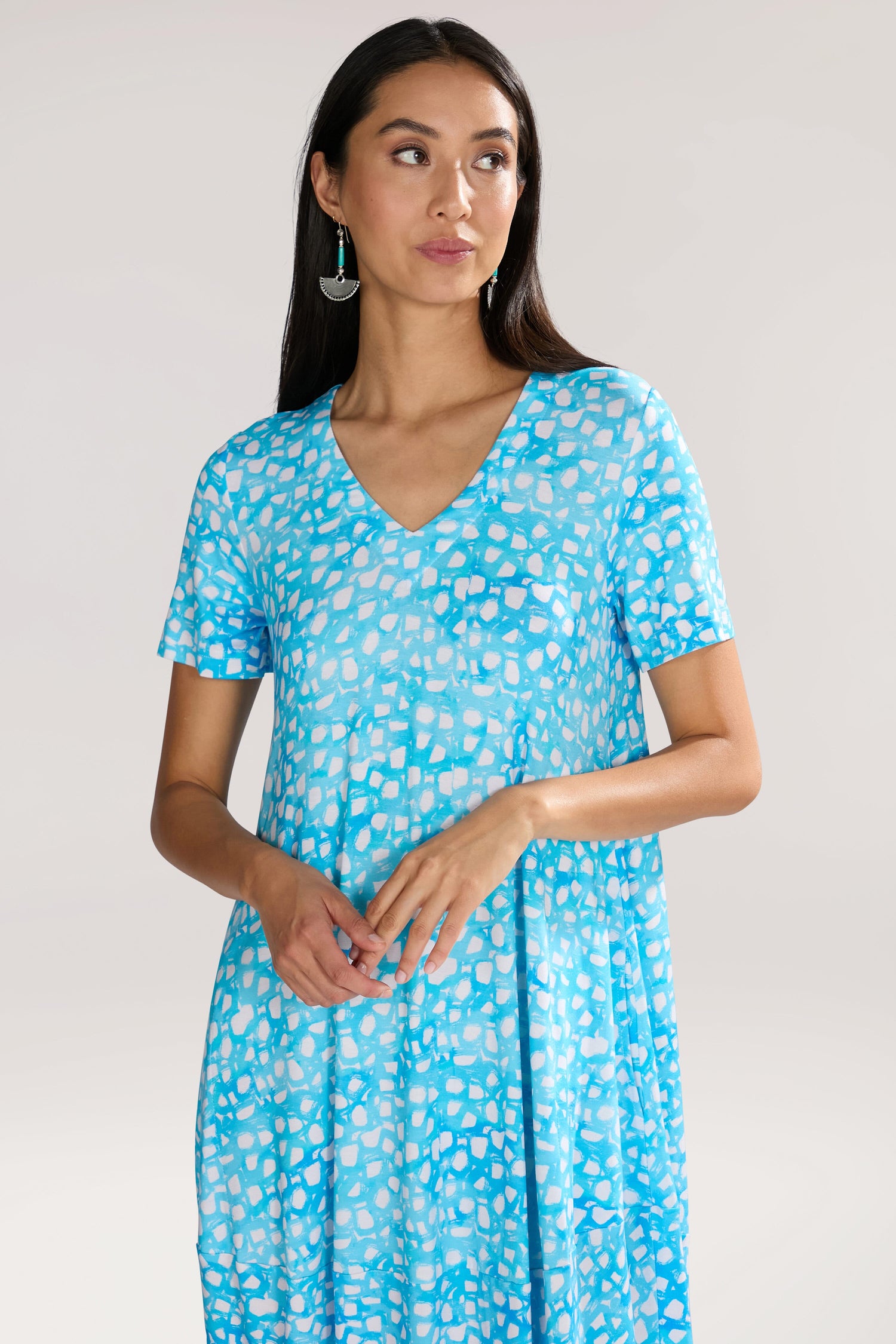 Woman wearing a Pebble Jersey Print Bubble Dress, looking to the side with hands clasped.