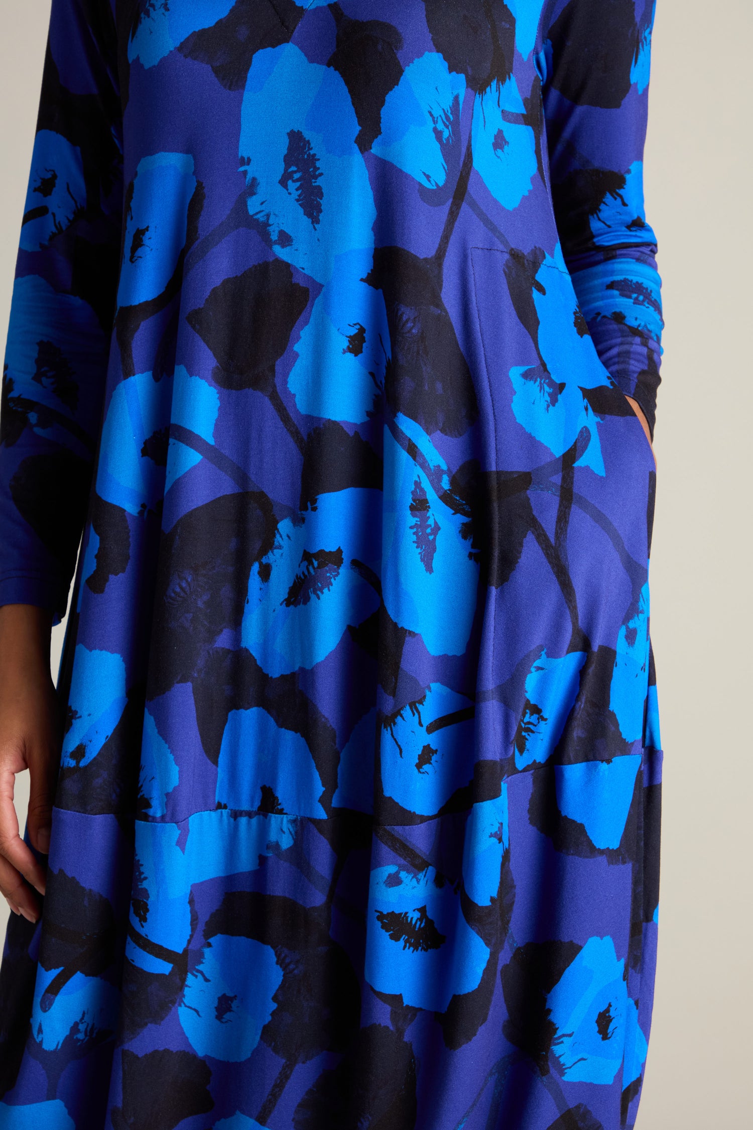 Close-up of a person wearing the Flowering Poppies Bubble Dress, featuring a long-sleeved design with a blue and black poppy print in an abstract floral pattern and contemporary silhouette.