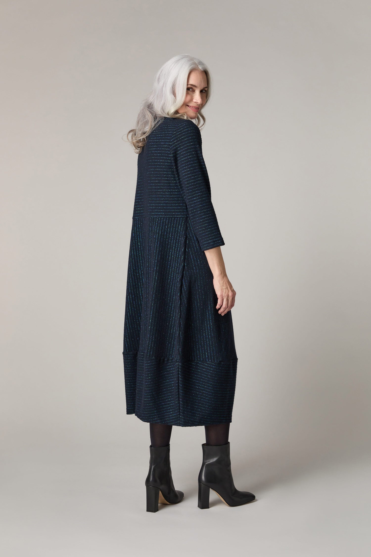 The back view of a woman wearing a Stripe Lurex Jersey Dress with stripes.