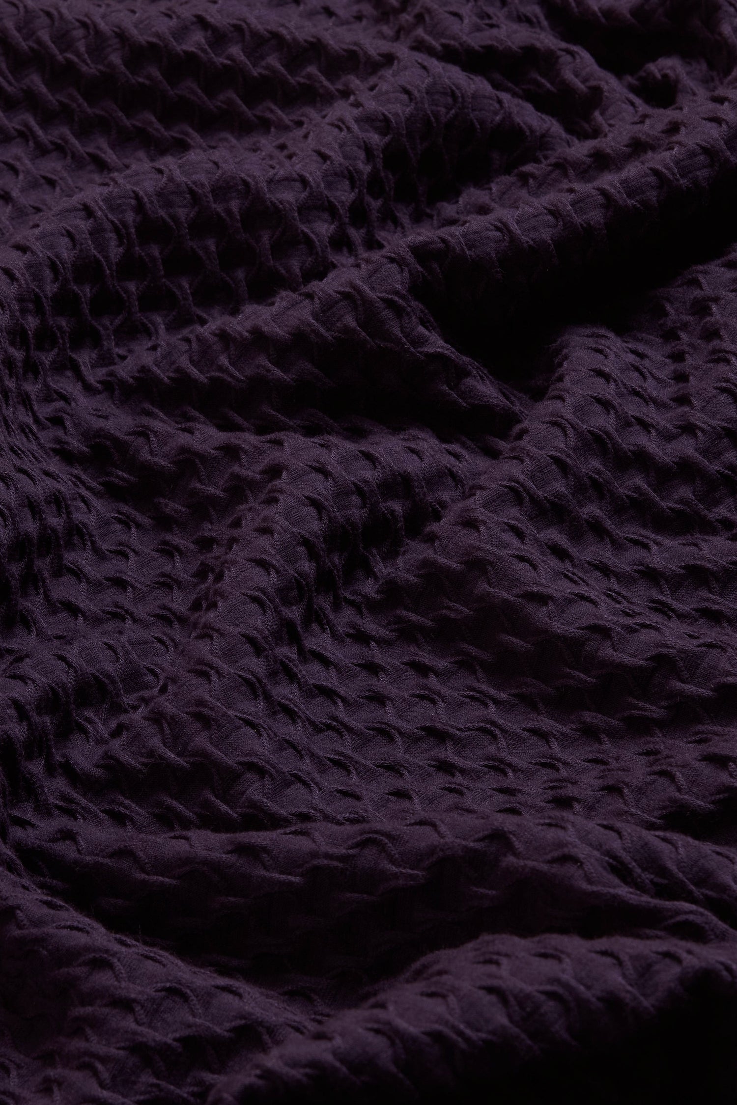 Close-up of the Damson Waffle Textured Jersey Bubble Dress, featuring a dark purple color with a wavy, crinkled surface and a subtle repeating pattern.
