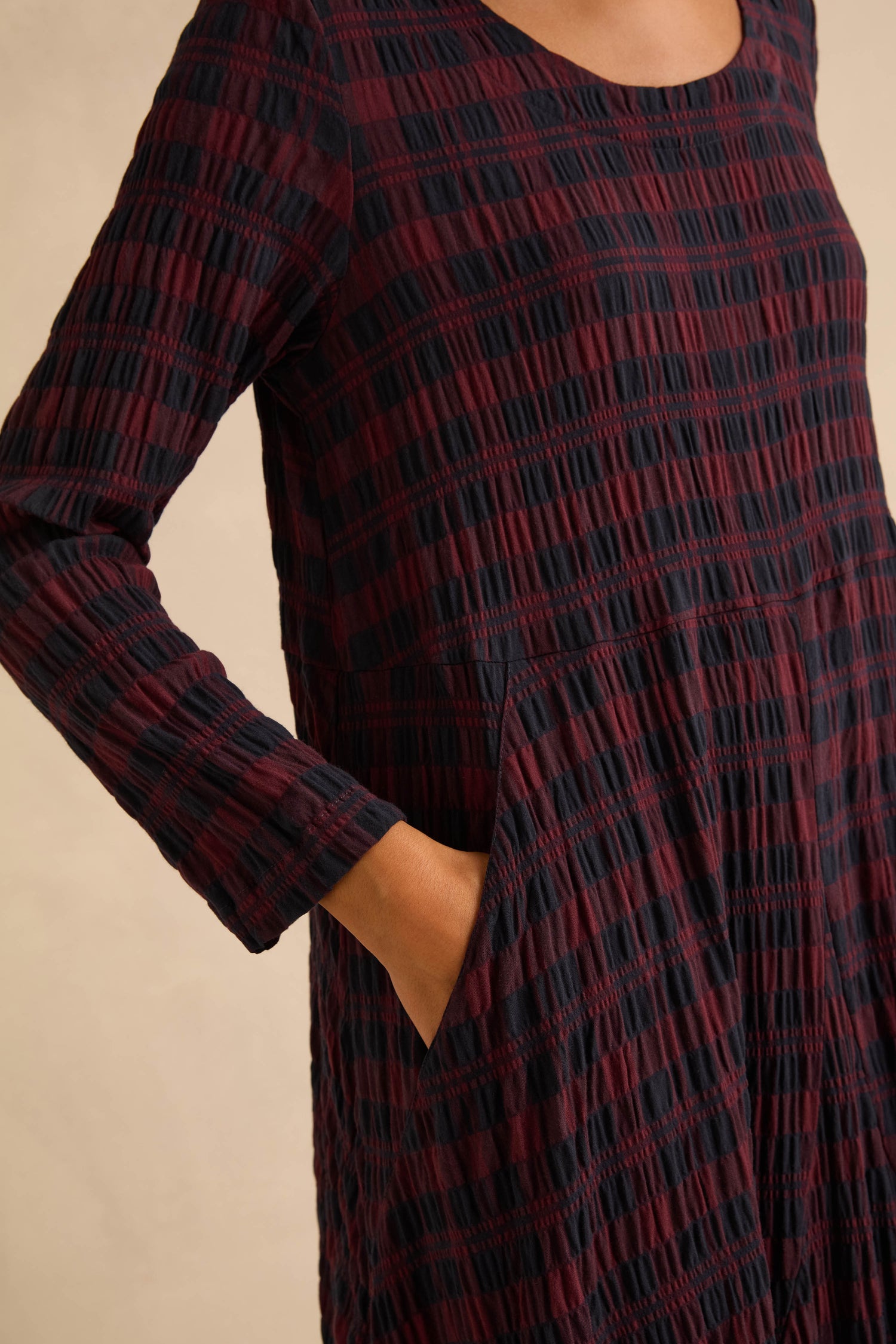 Crinkle Check Bubble Dress in a long-sleeved, midi length crinkle check maroon and black plaid pattern with side pockets.