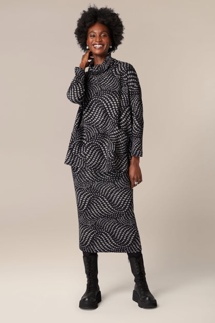 A woman wearing a Spiral Spot Jersey Tube Skirt and jacket made of jersey material.