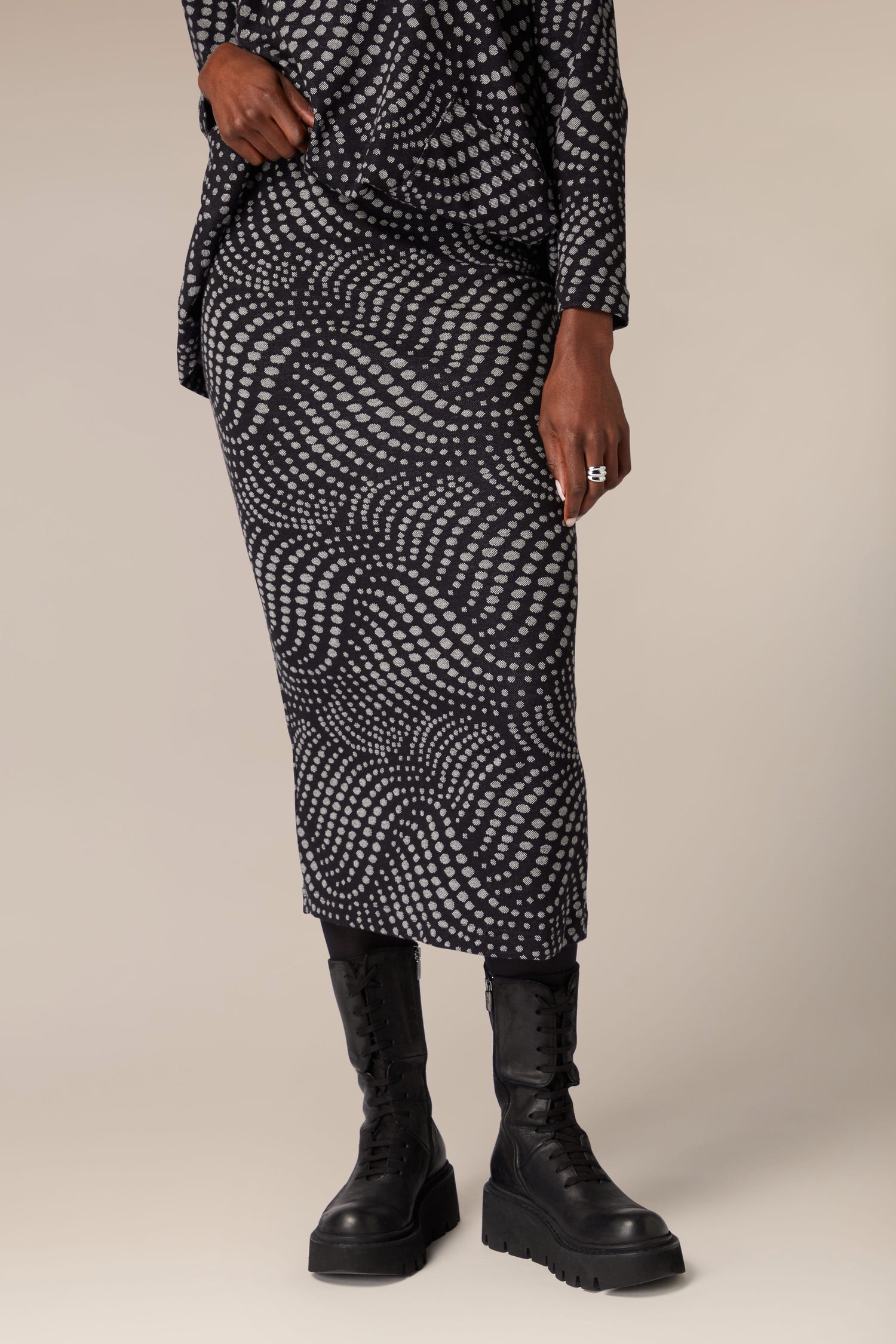 A woman wearing a Spiral Spot Jersey Tube Skirt, a unique black and white spot pattern skirt.