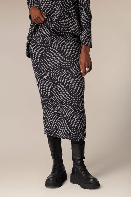 A woman wearing a Spiral Spot Jersey Tube Skirt, a unique black and white spot pattern skirt.