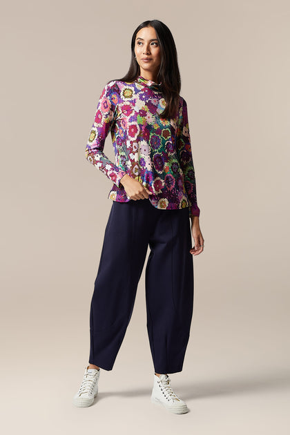 A moody woman wearing a Midnight Garden Jersey Polo Neck and navy trousers.