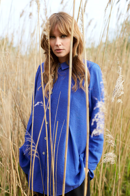 A woman in a Textured Viscose Pleat Shirt standing in tall grass on a special occasion.