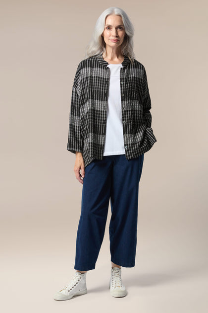 A silhouette of a woman wearing a Gradient Check Shirt and blue pants.