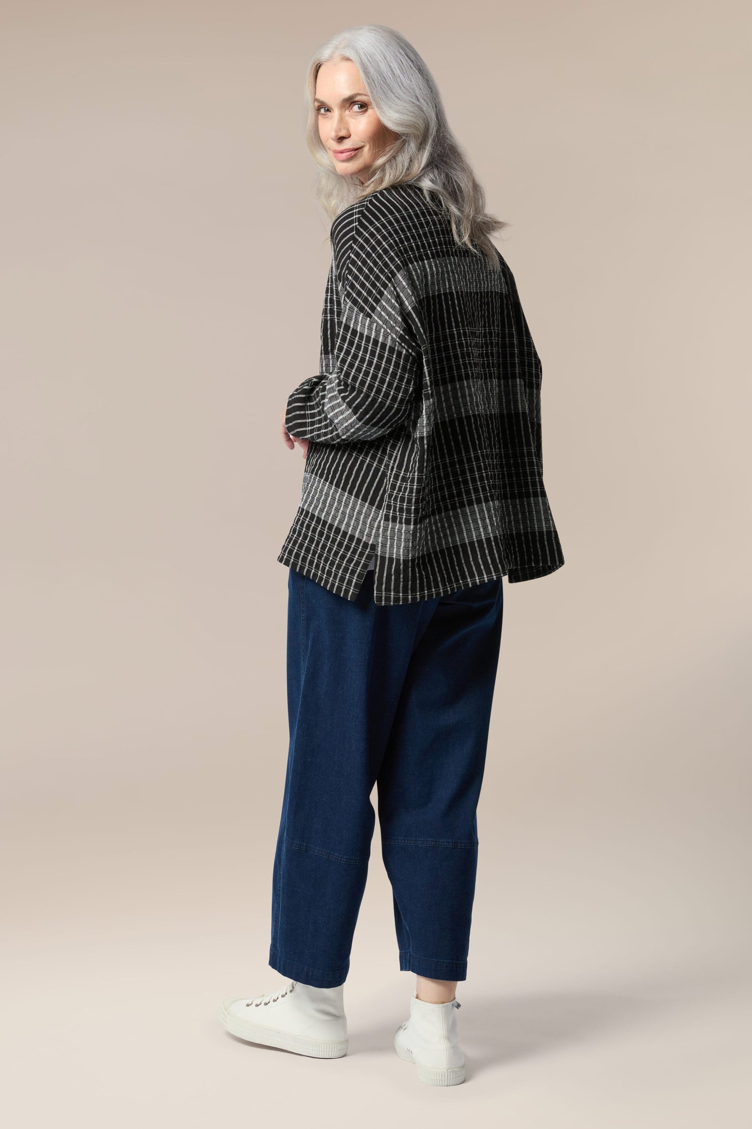 The back view of a woman wearing a Gradient Check Shirt and blue pants, exuding comfort and showcasing her silhouette.