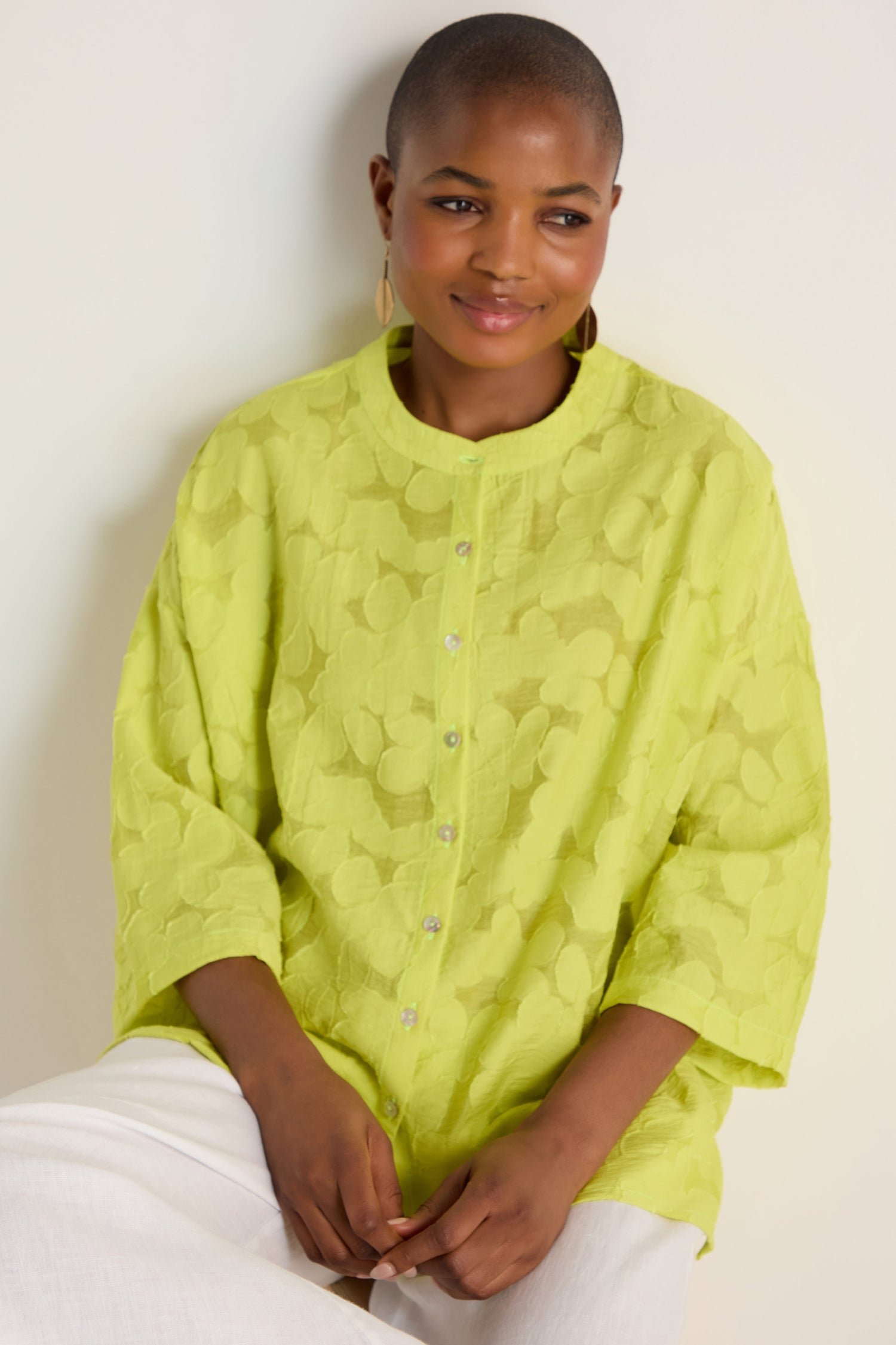 A person with short hair wears the Etched Floral Viscose Shirt in light green and white pants, sitting against a plain light background.