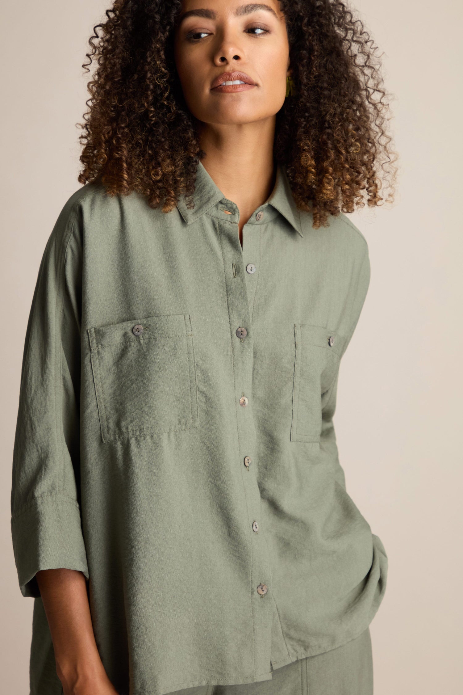 A person with curly hair wearing an oversized, boxy green Textured Viscose Boxy Shirt looks slightly to the side against a neutral background.