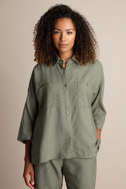 A person with curly hair wears a sage green Textured Viscose Boxy Shirt with front pockets and matching Textured Viscose Bubble Trouser, standing against a neutral background.