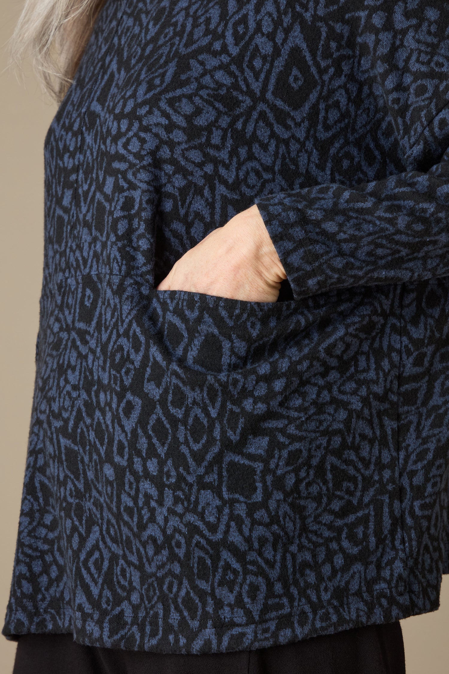 Close-up of a person wearing the Ikat Soft Jersey Relaxed Top, featuring an abstract blue and black pattern, with their hand in a pocket.