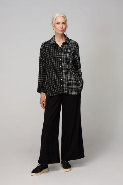An older woman with gray hair stands facing forward, wearing the Crinkle Window Check Boxy Shirt, wide-leg black pants, and black shoes against a plain light background.