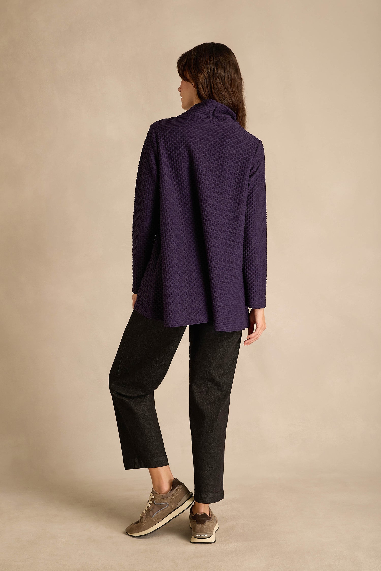 A person stands with their back to the camera, wearing the Waffle Textured Jersey Damson Cowl Neck Top, black pants, and taupe sneakers against a neutral background.