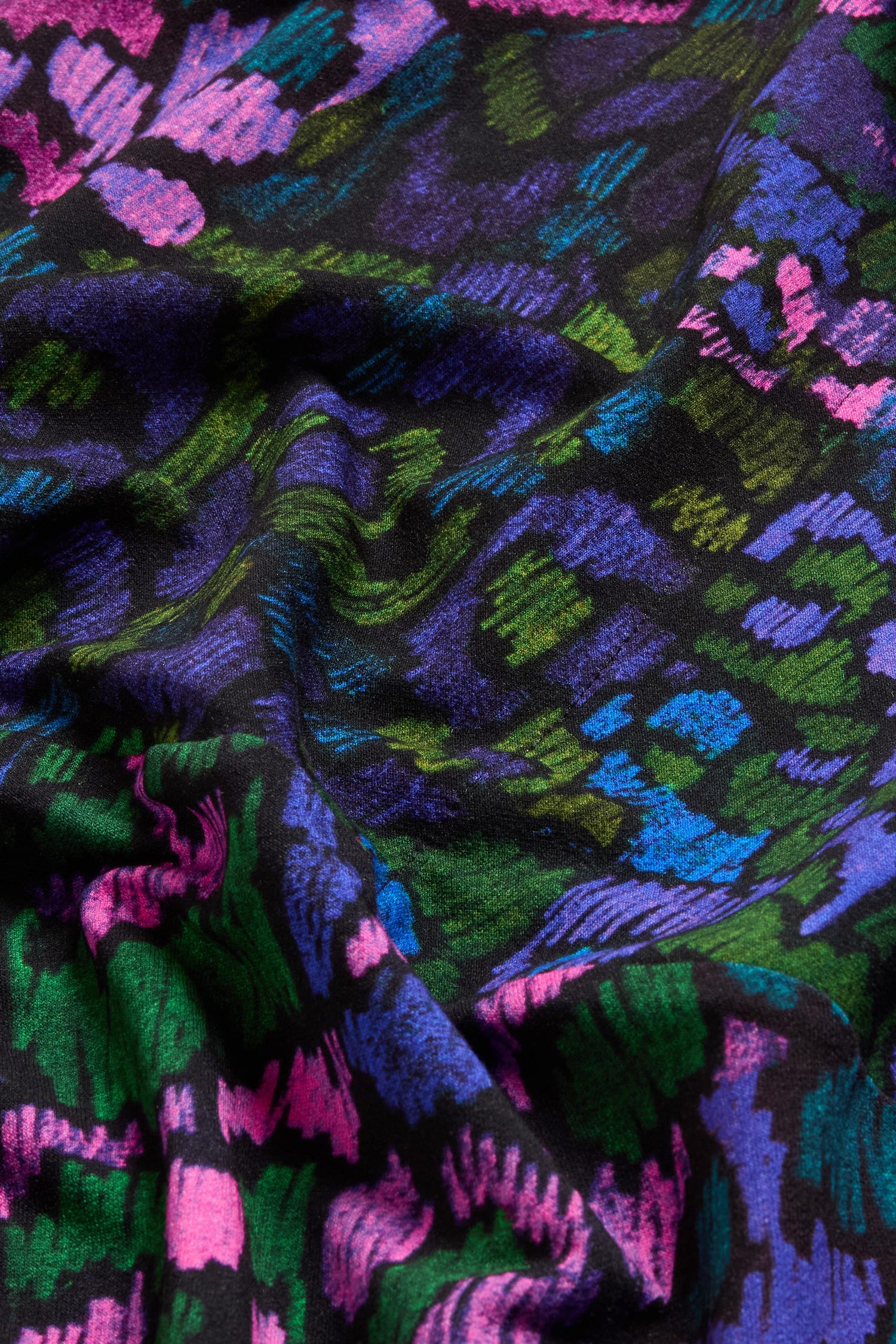 The Winter Garden Jersey Cowl Neck Top features a wrinkled jersey fabric with an abstract pattern in pink, purple, blue, and green on a black background—ideal for creating a cowl neck style or a fit-and-flare silhouette.