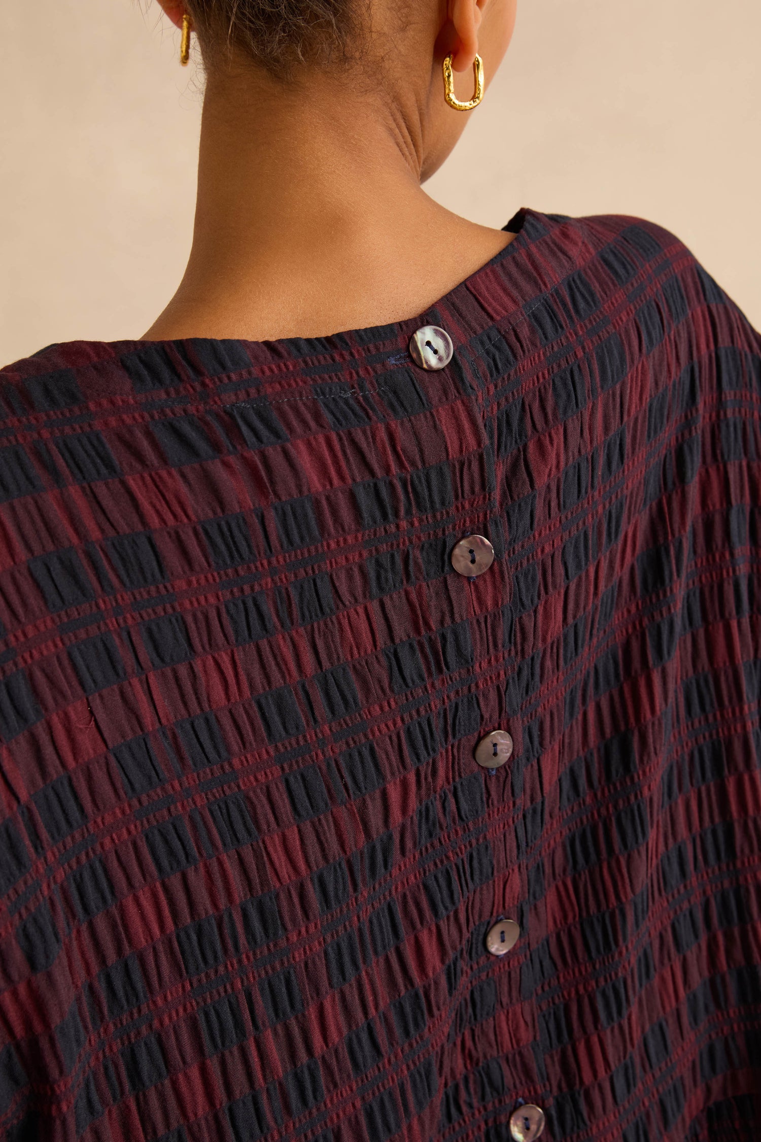 Back view of a person wearing the dark red and black Crinkle Check Bubble Dress, featuring a button-down back and bubble skirt.