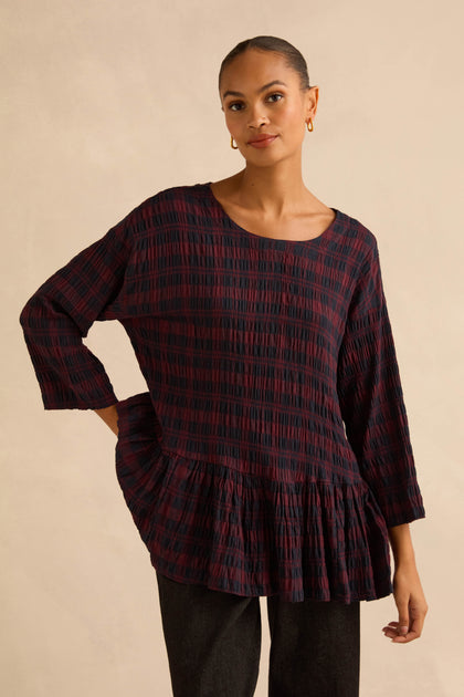 A model wears a dark red and black Crinkle Check Frill Hem Top, featuring long sleeves and a ruffled peplum hem.