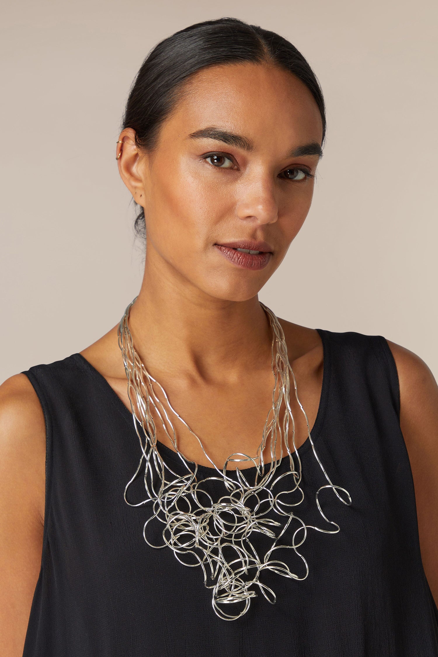 A woman wearing a black top and a statement Long Medley Necklace.