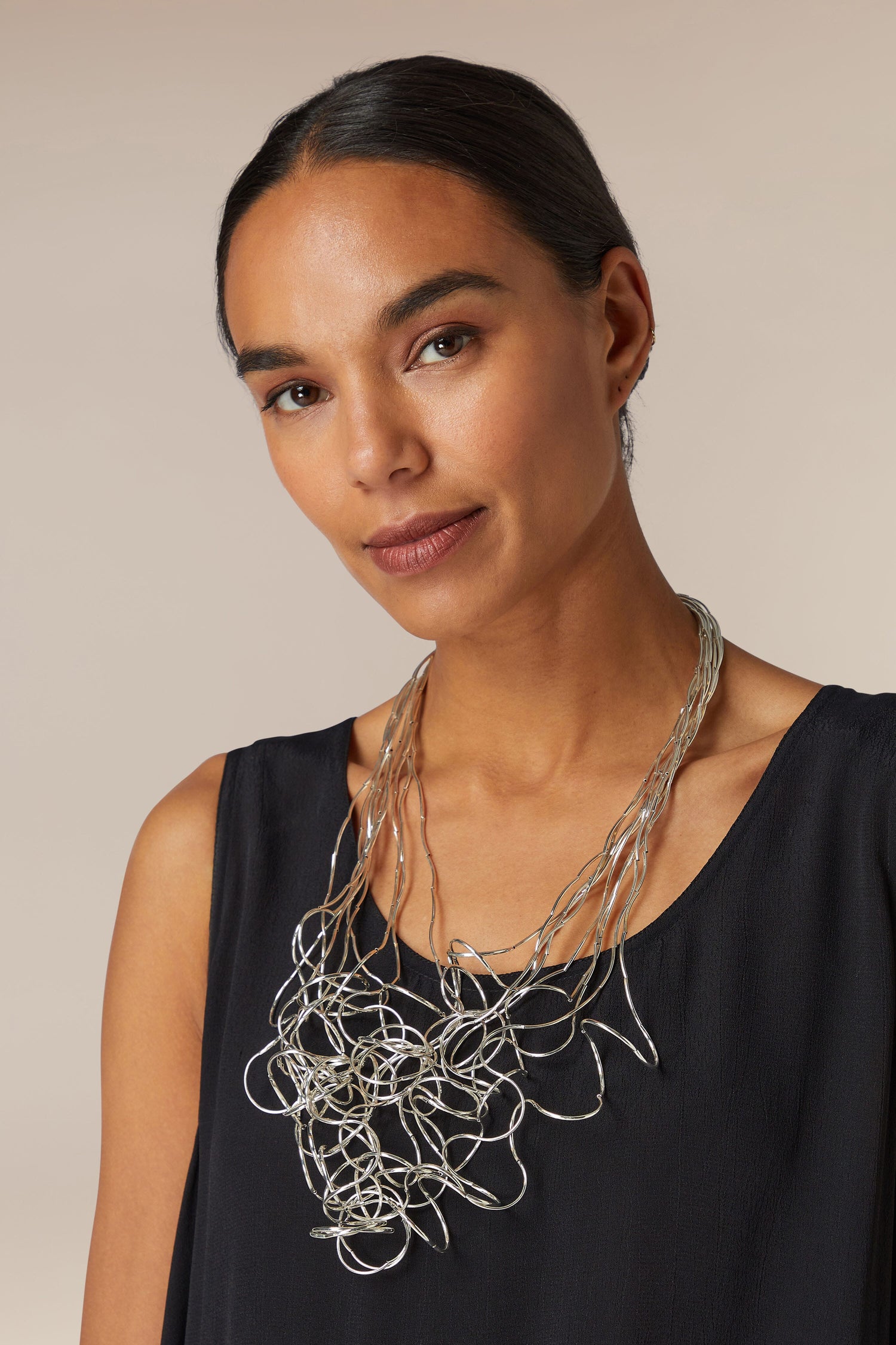 A woman wearing a black top and a statement Long Medley Necklace.